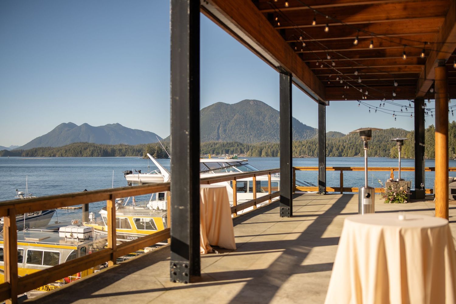 Waterfront restaurant deck with mountain views and elegant table settings.