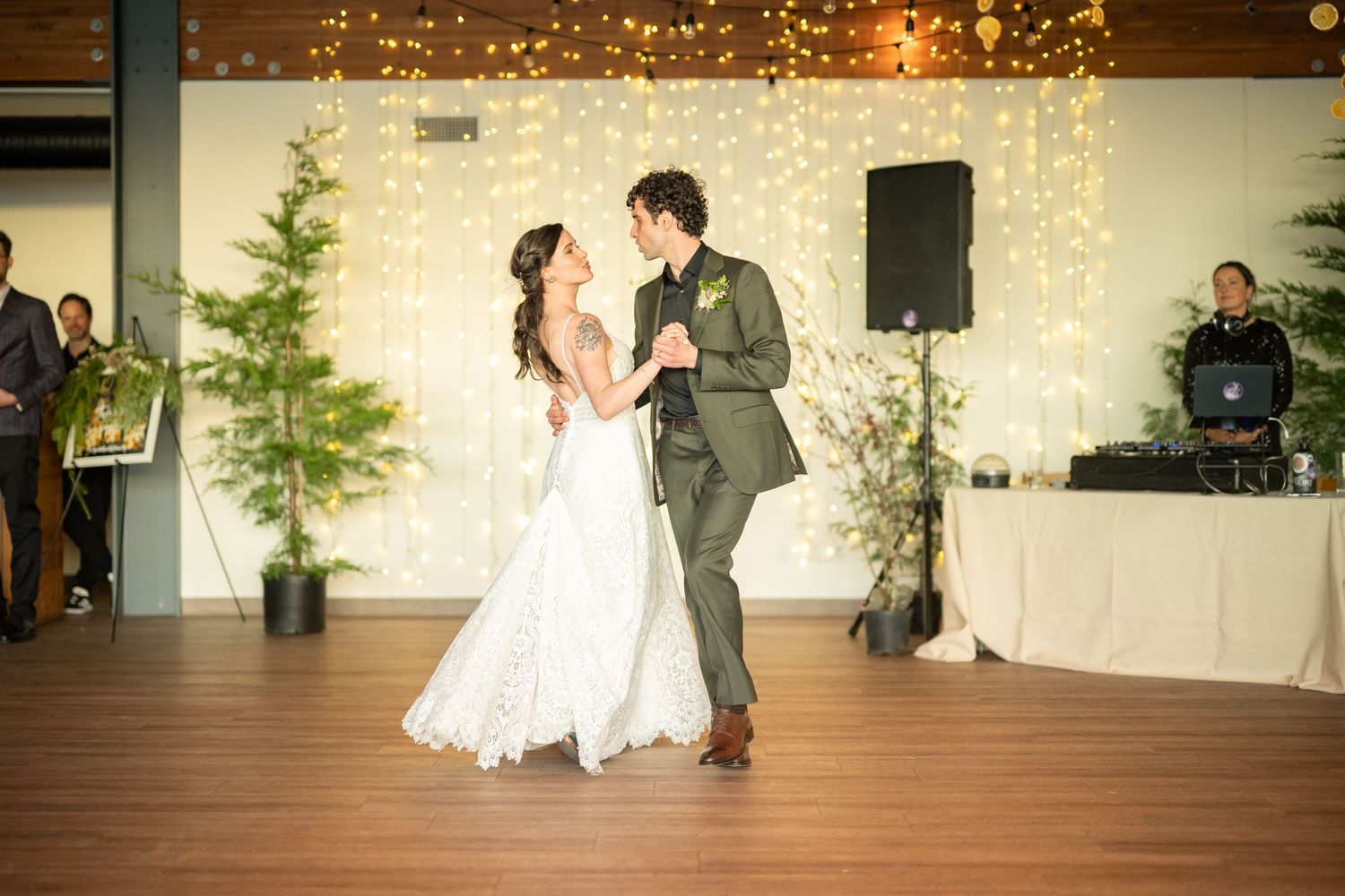 Wedding celebration in rustic venue with string lights and exposed wooden beams.