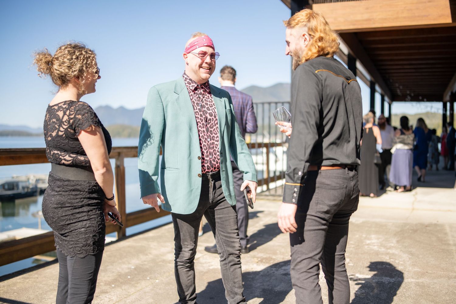 Guests mingling on outdoor deck overlooking waterfront.