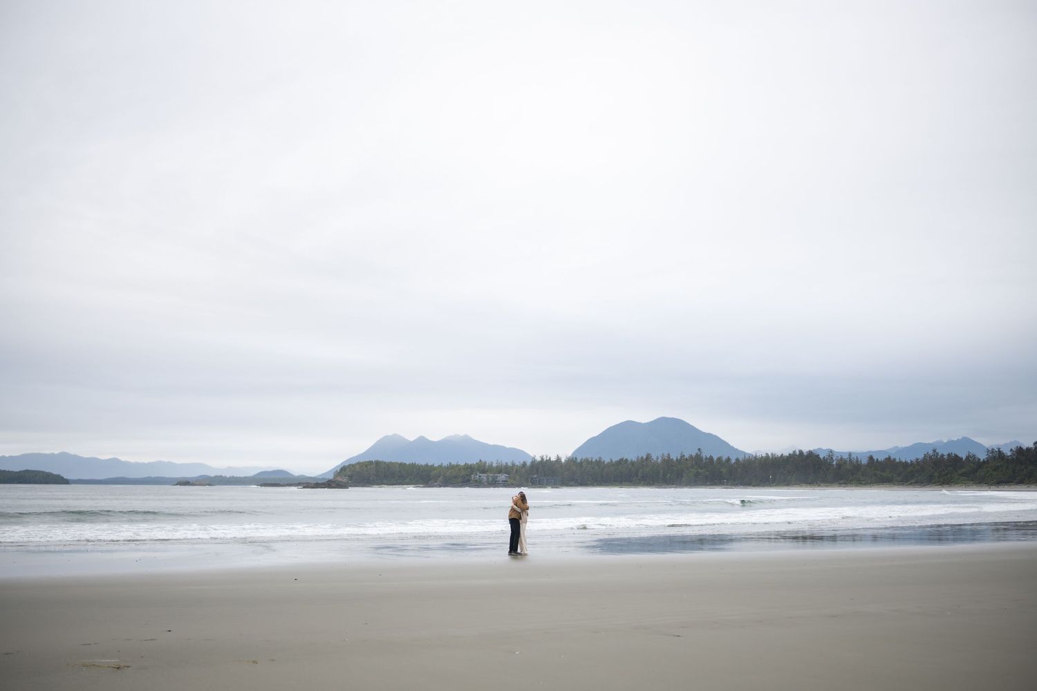 Serene beach panorama with mountains and cloudy skies along the Pacific coast.