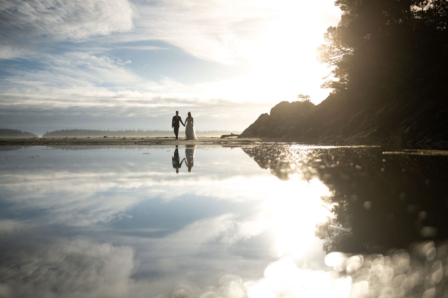 Stunning sunset reflection on calm water with silhouettes against bright sky.