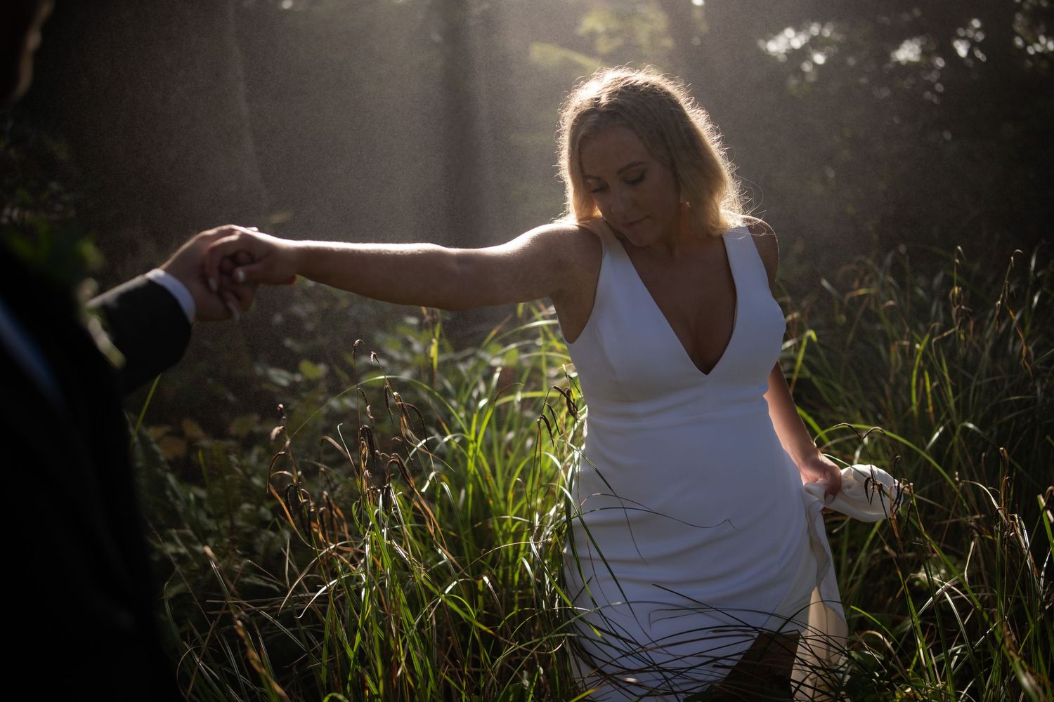 Sunlit wedding portraits in natural outdoor setting with greenery.