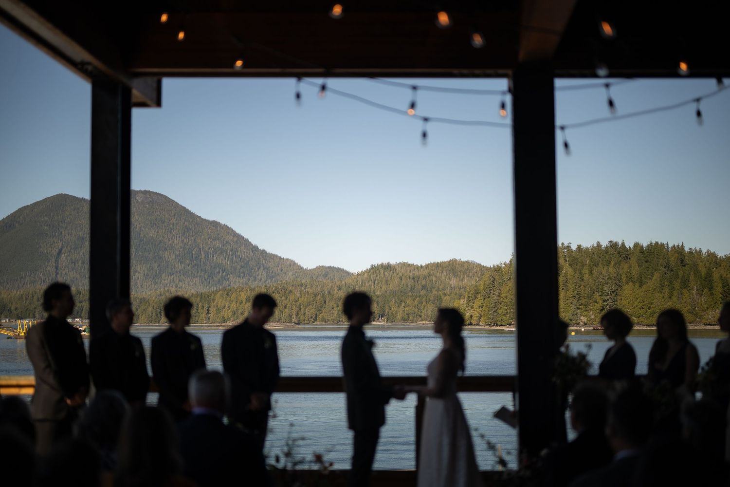Silhouetted wedding ceremony against dramatic mountain and lake backdrop.