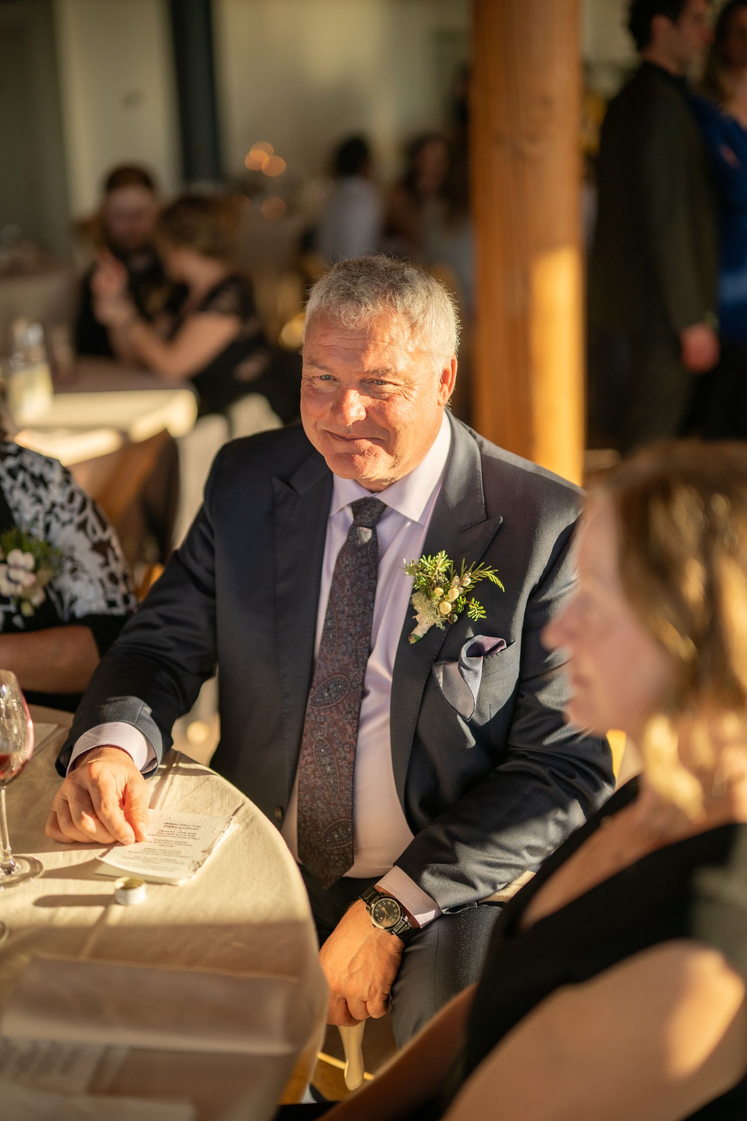 Elegant dinner reception with guests seated at tables in warm lighting.