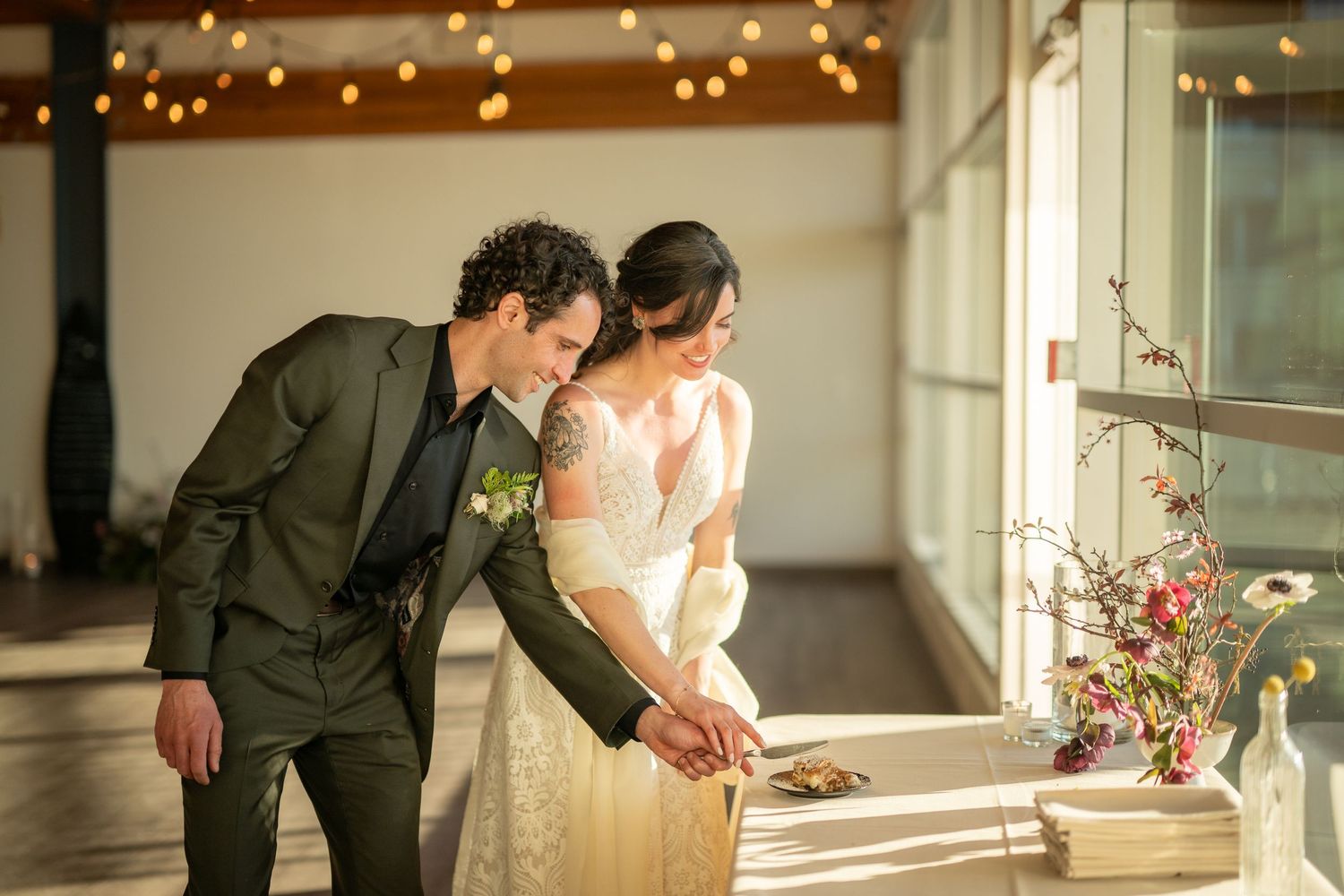 Wedding reception venue decorated with string lights and natural sunlight streaming in.