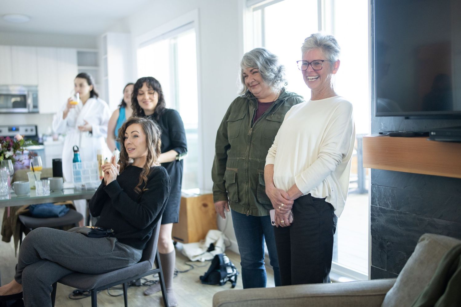 A casual gathering of people in a bright modern living room with large windows.