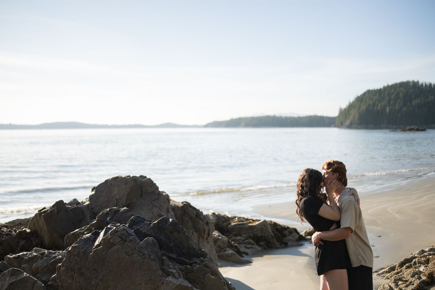 Panoramic view of a Pacific Northwest beach with rocky outcrops and forested islands.