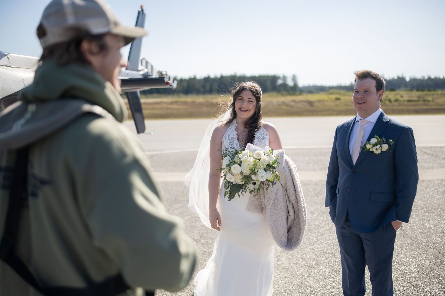 Wedding ceremony participants walking on an airfield tarmac.