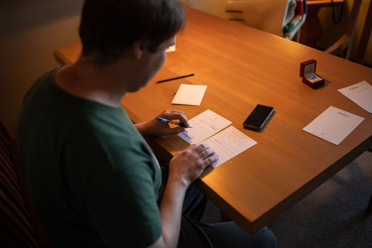 Wooden conference table in dim lighting with papers and devices scattered across it.