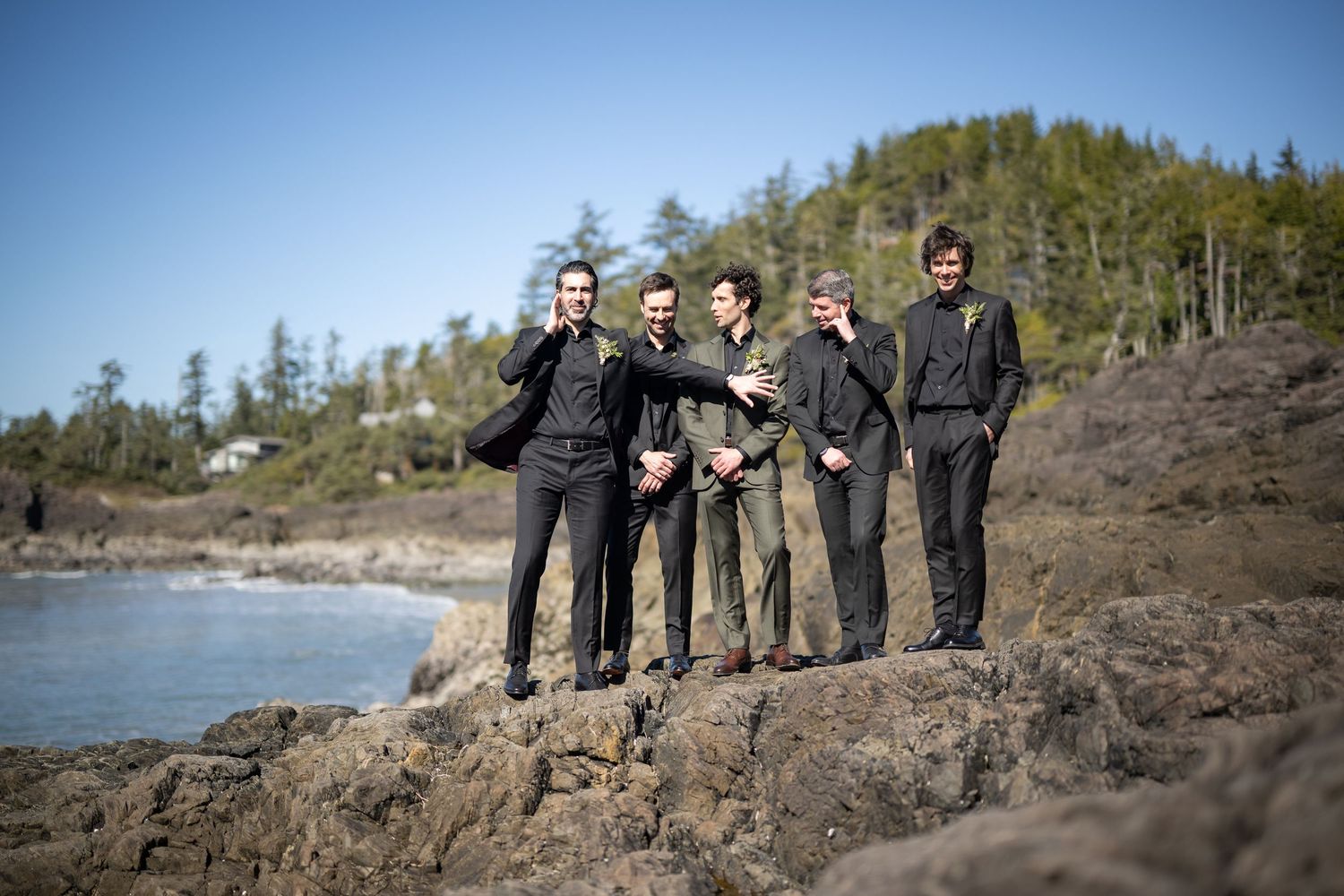 Group walking along rocky coastal path with ocean views on sunny day.