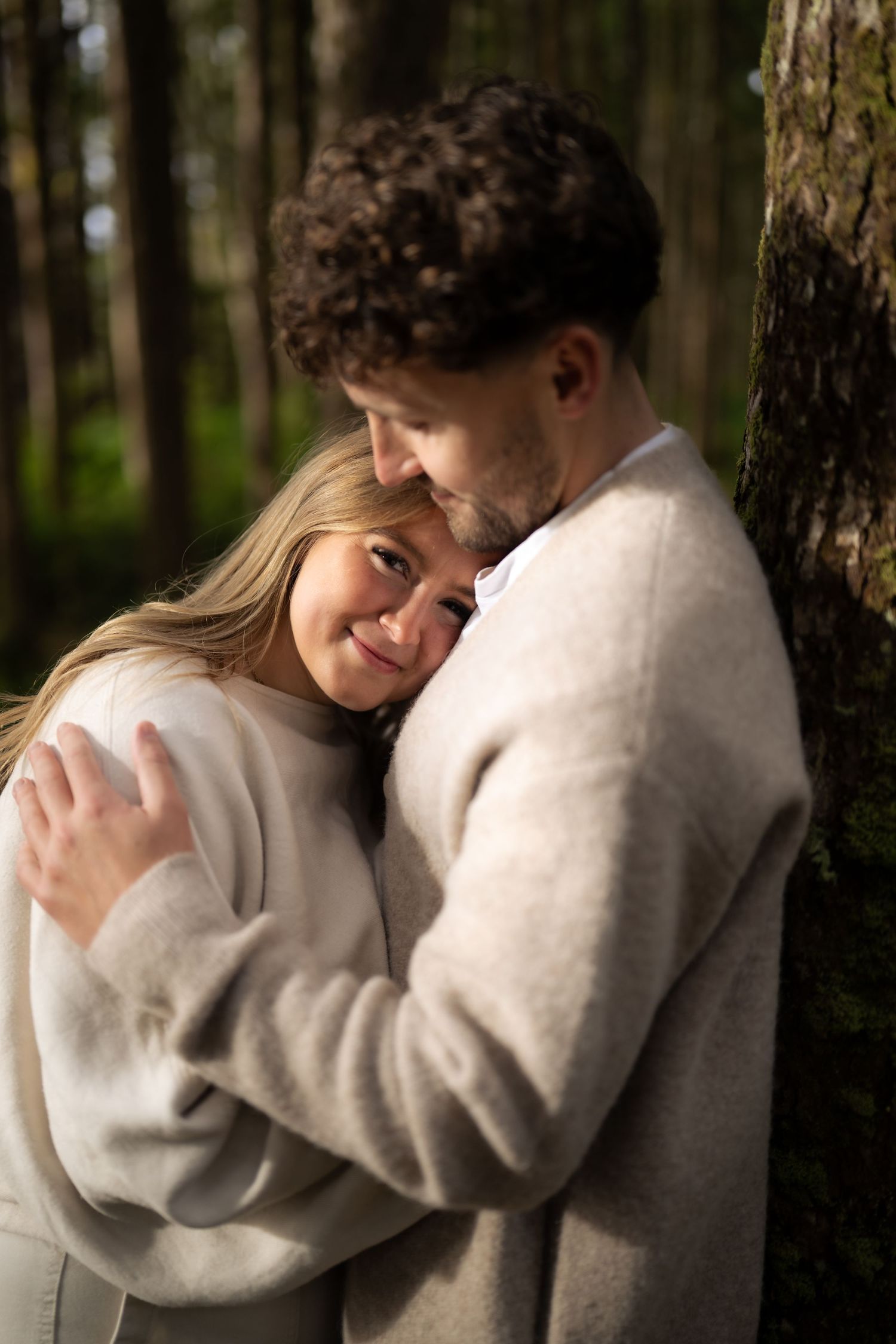 Intimate moments captured in a sequence of tender embraces among tall forest trees.