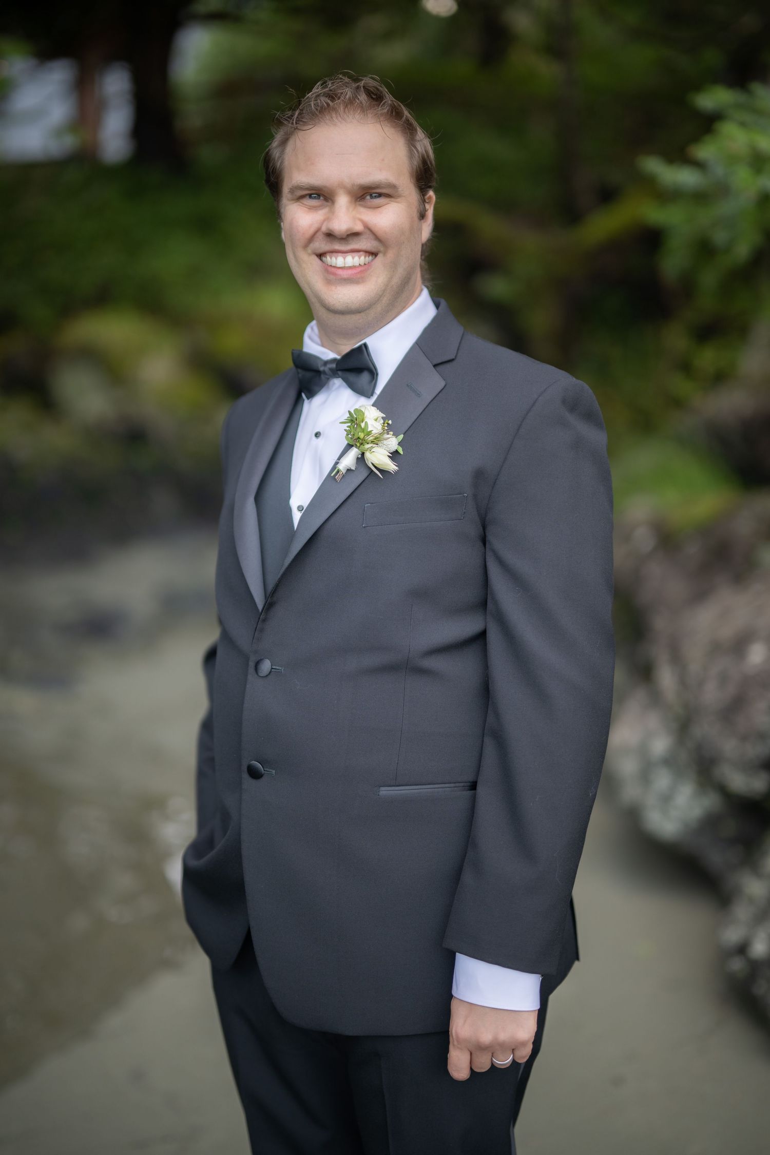 A formal black tuxedo with white boutonniere against a green background.