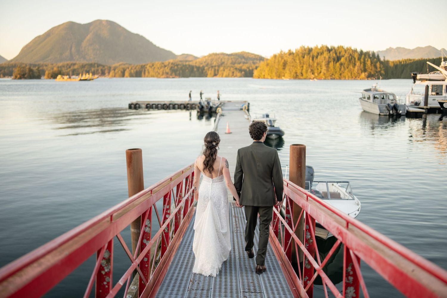 Red dock walkway leading to a scenic waterfront view with mountains in the distance.