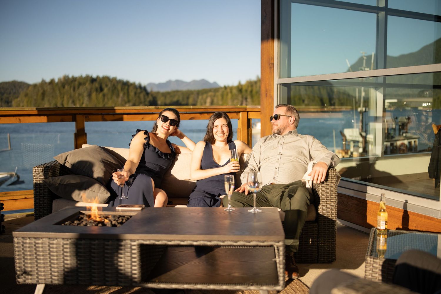 Guests relaxing on a waterfront deck with mountain views at sunset.