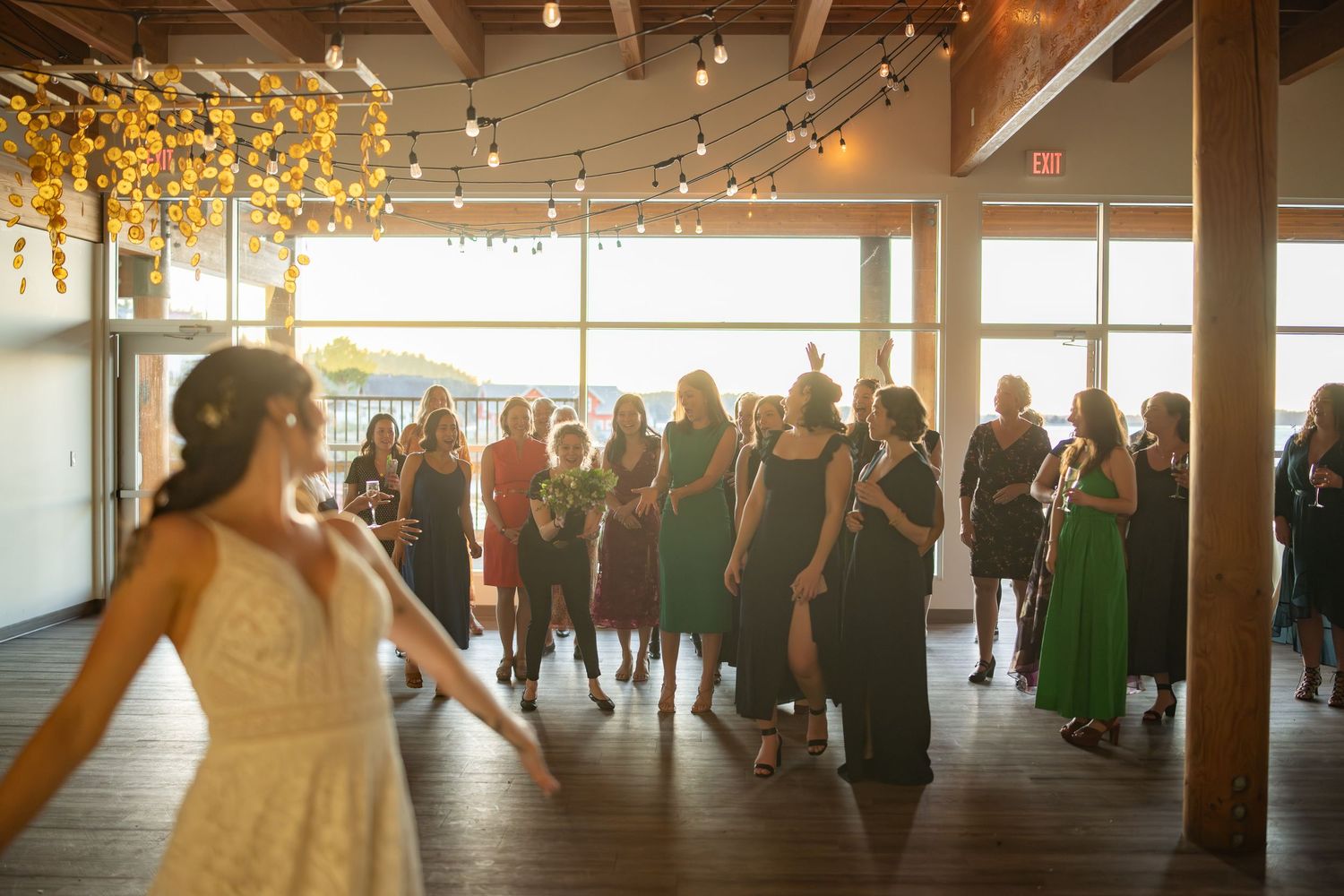 Wedding reception venue with large windows and guests gathering on dance floor.