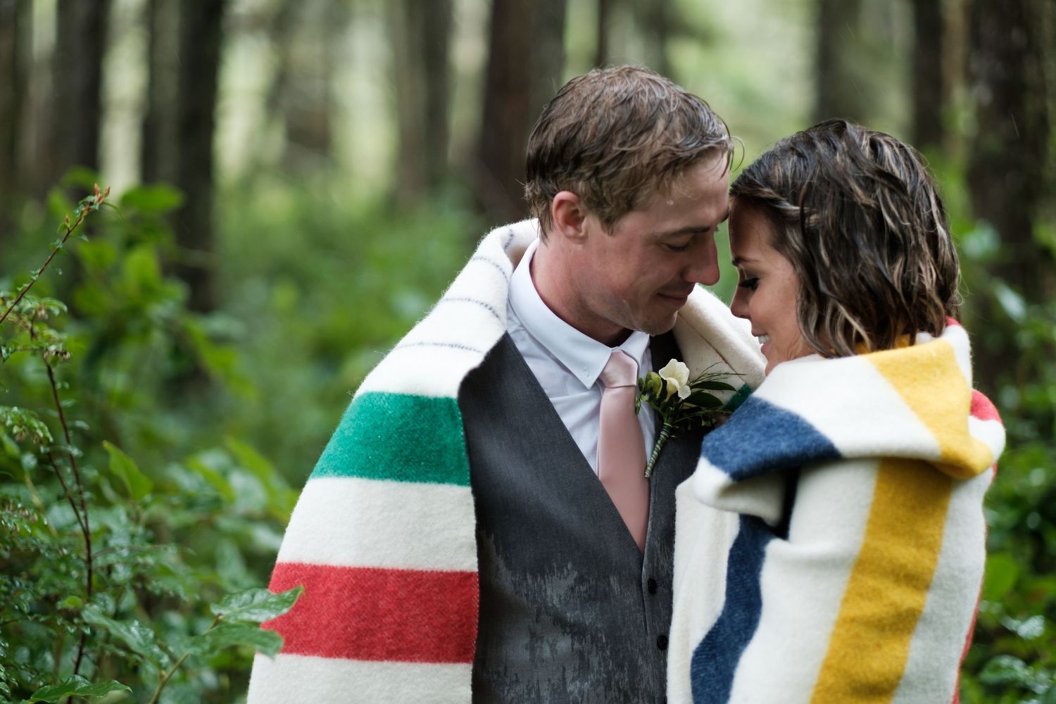 A couple embraces in a romantic outdoor setting surrounded by lush greenery.