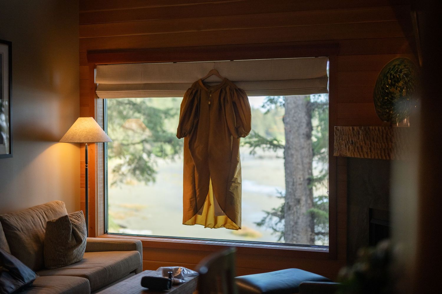 Cozy interior room with window showing trees outside and warm lamp lighting.