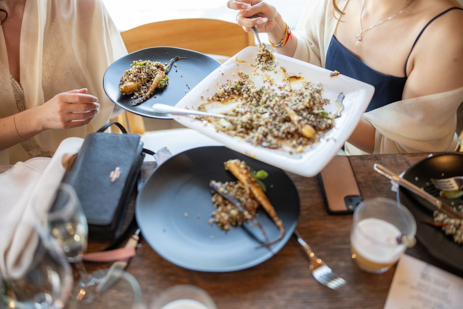 Diners sharing plates of gourmet food at a restaurant table.