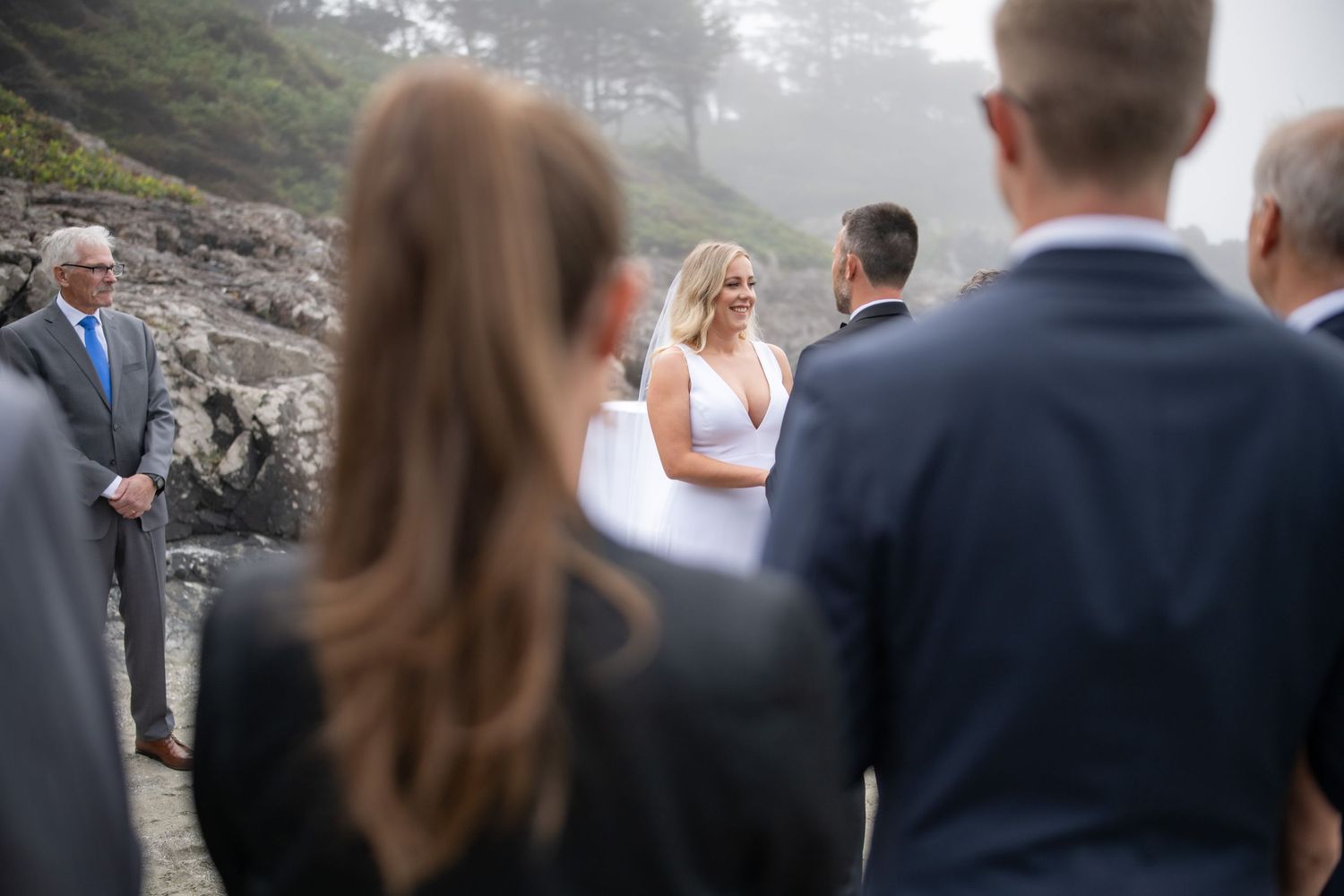 A wedding ceremony in progress on a misty coastal beach.