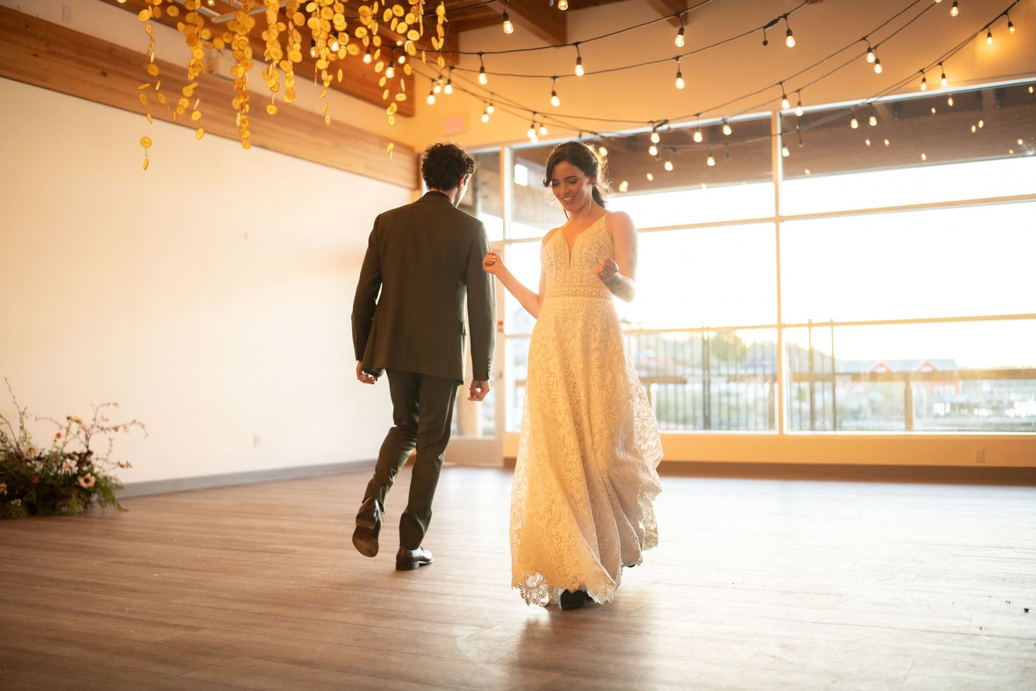 Large dance floor with string lights overhead in rustic wedding reception venue.