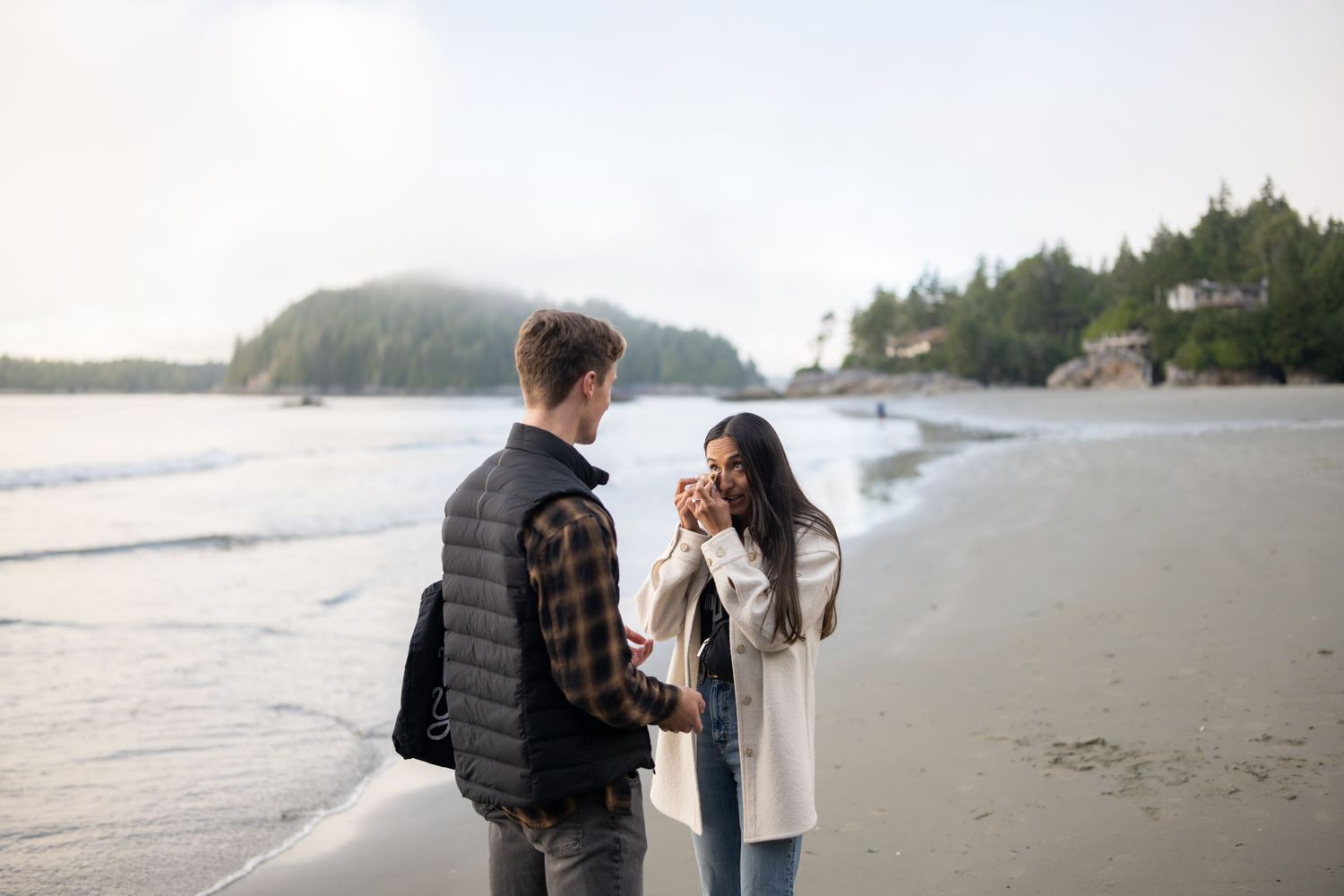 Peaceful beach setting with forested cliffs and gentle waves rolling in.