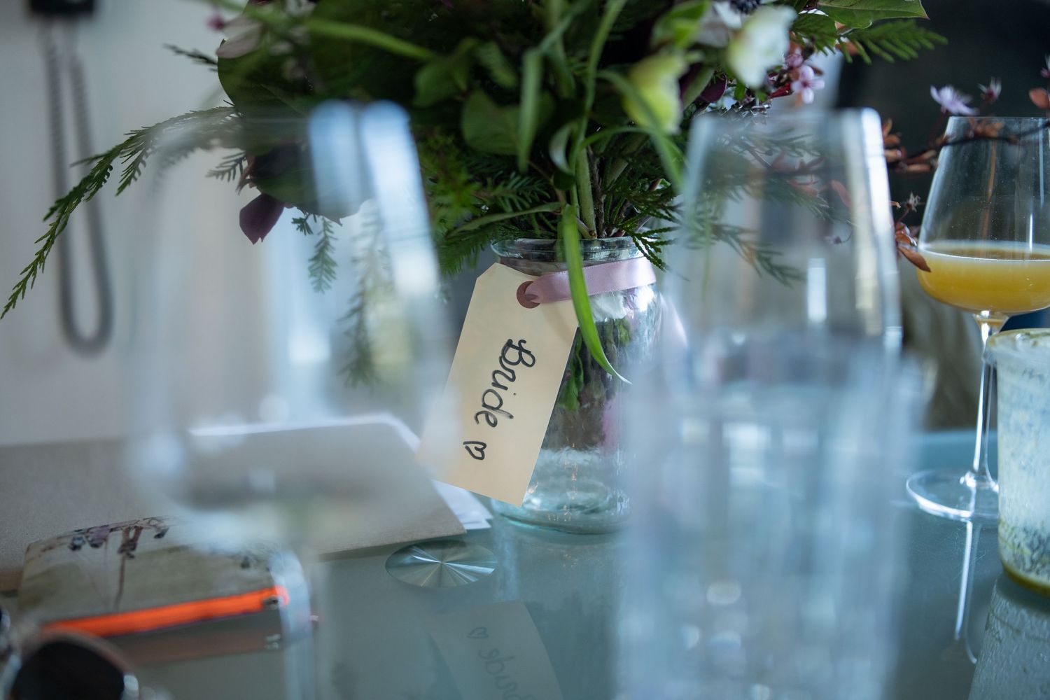 Fresh greenery and flowers arranged in glass vases on a table.