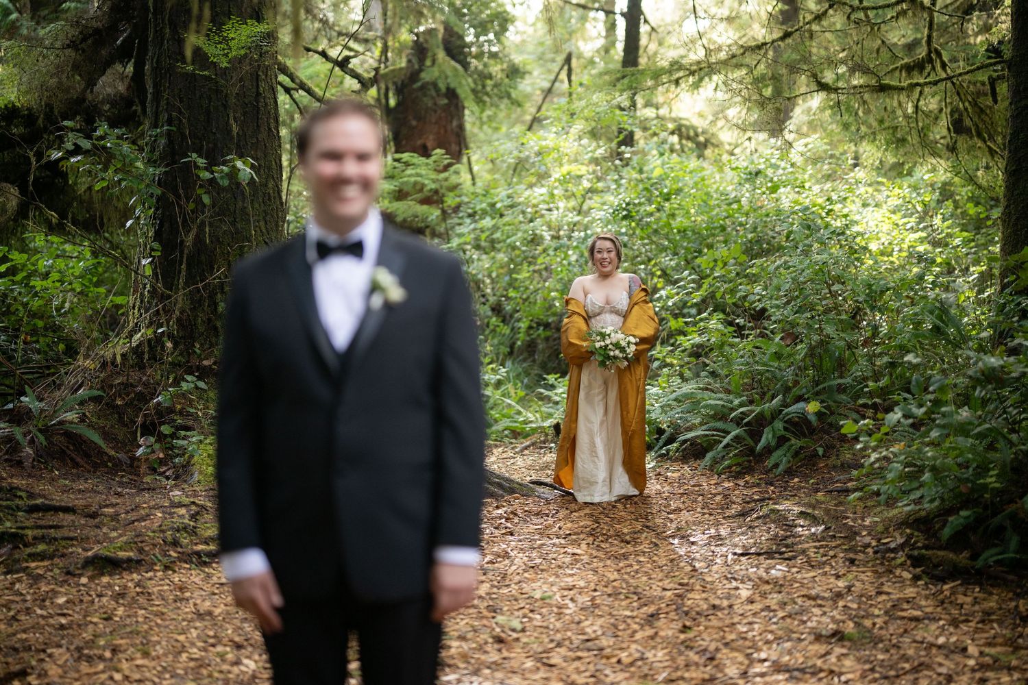 A forest wedding scene with figures standing among tall trees and dappled sunlight.