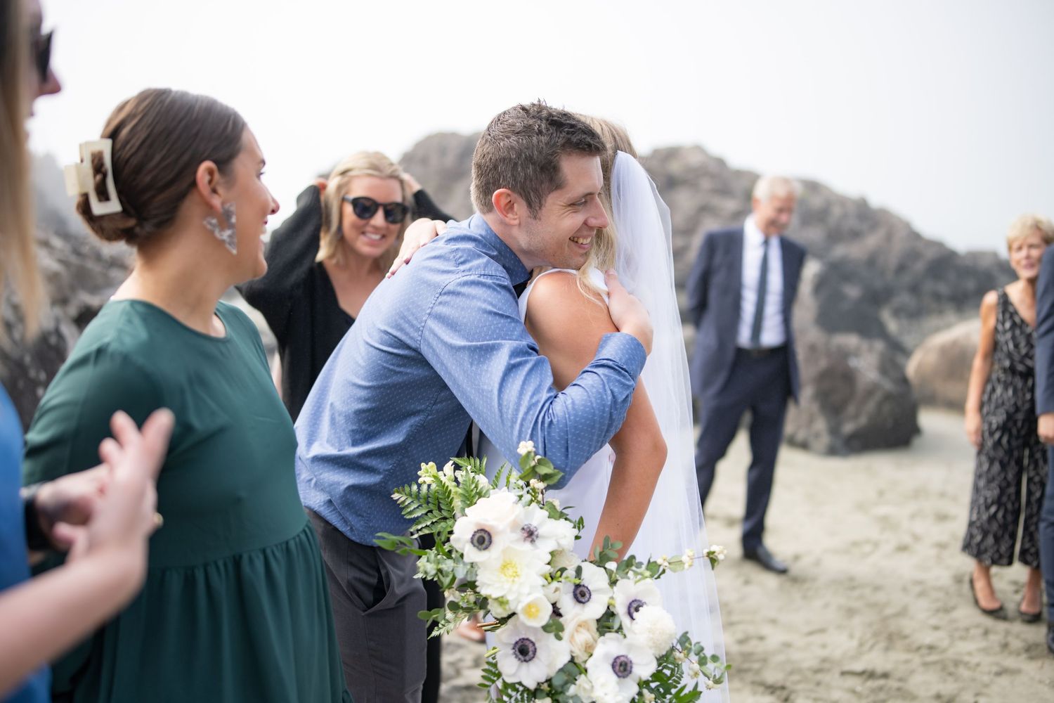 Candid moment during beach wedding celebration with guests in blue and green attire.