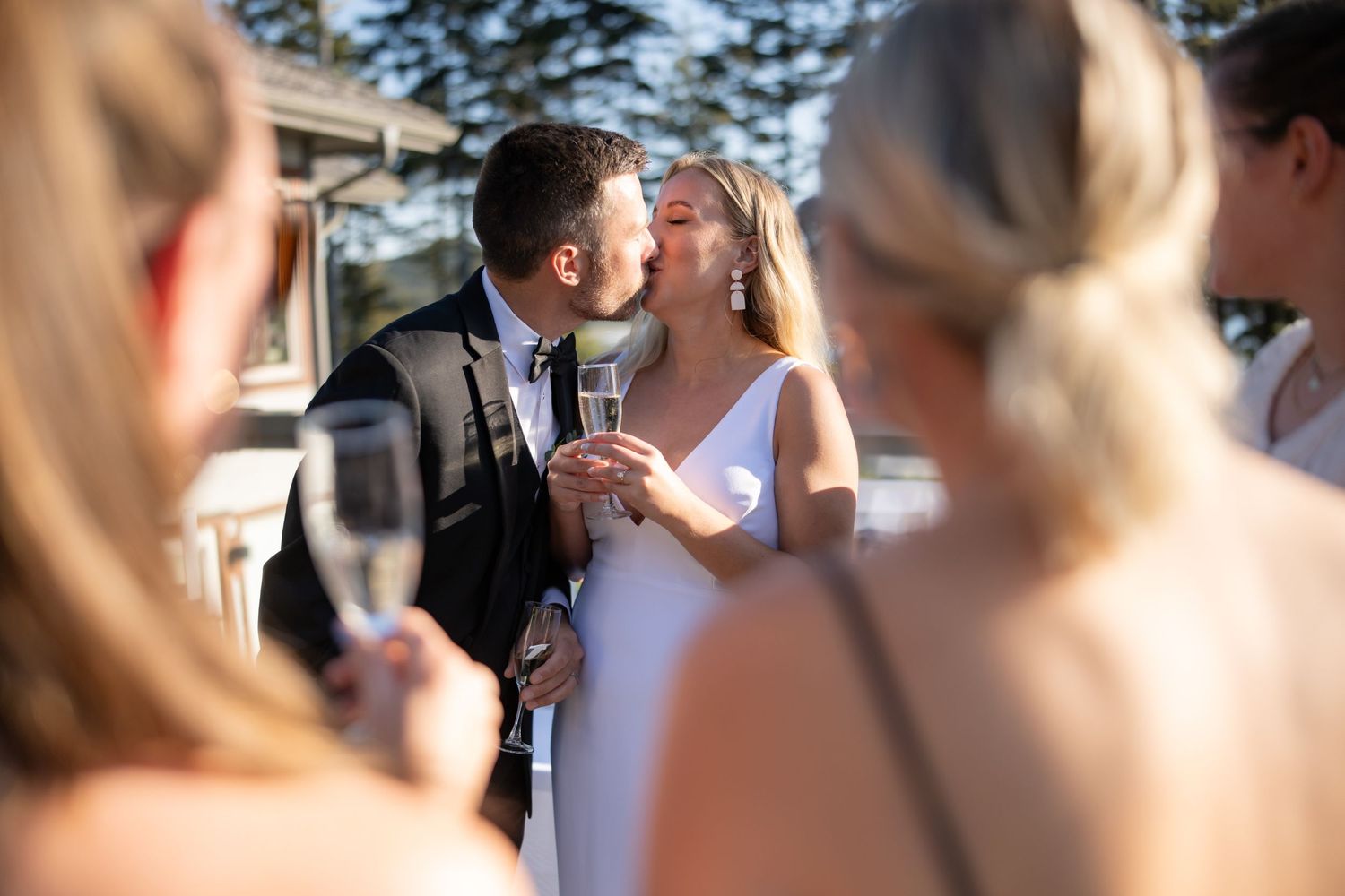 Intimate moment captured during outdoor wedding celebration with guests looking on.