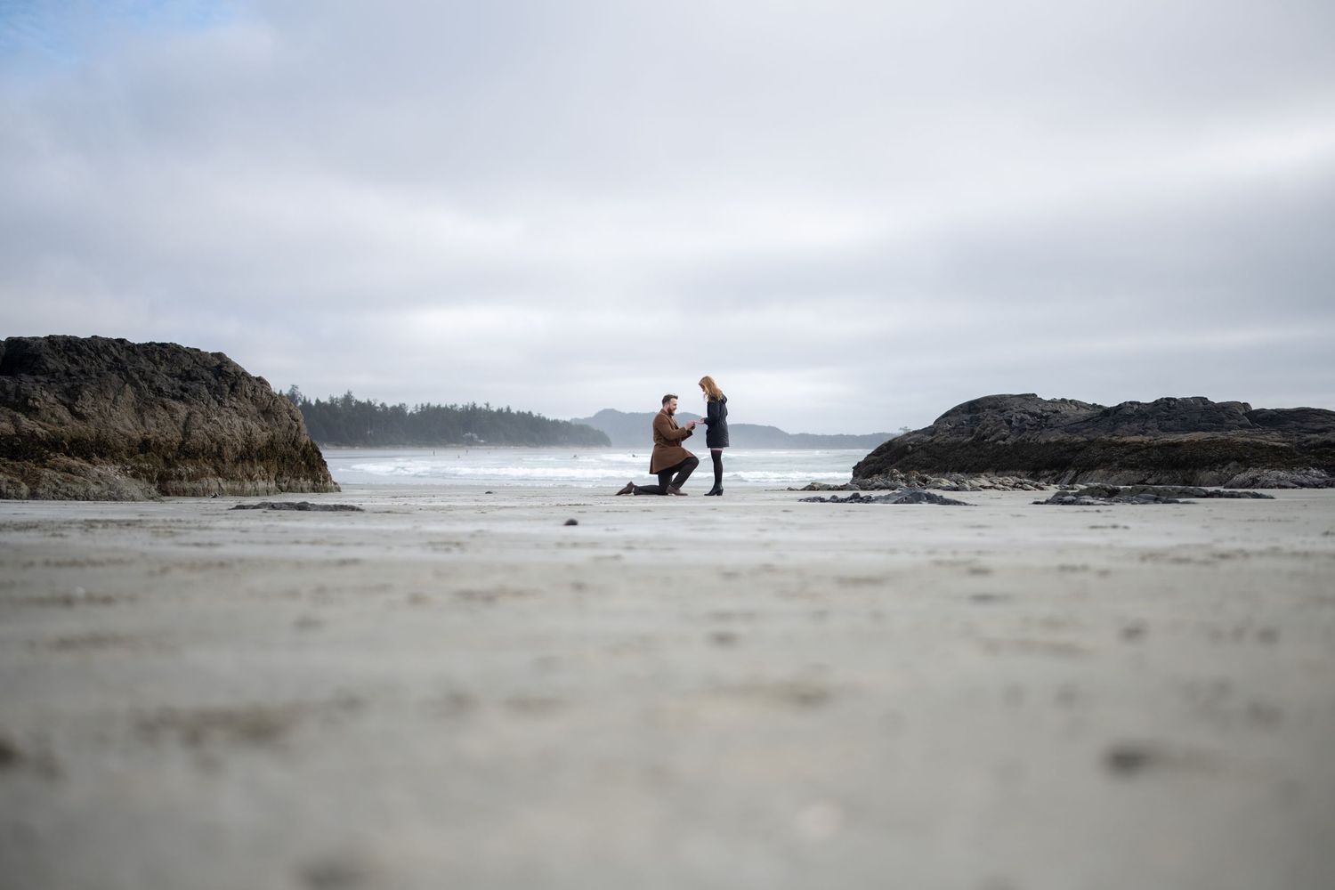 Minimalist beach landscape with distant figures against a misty coastline.
