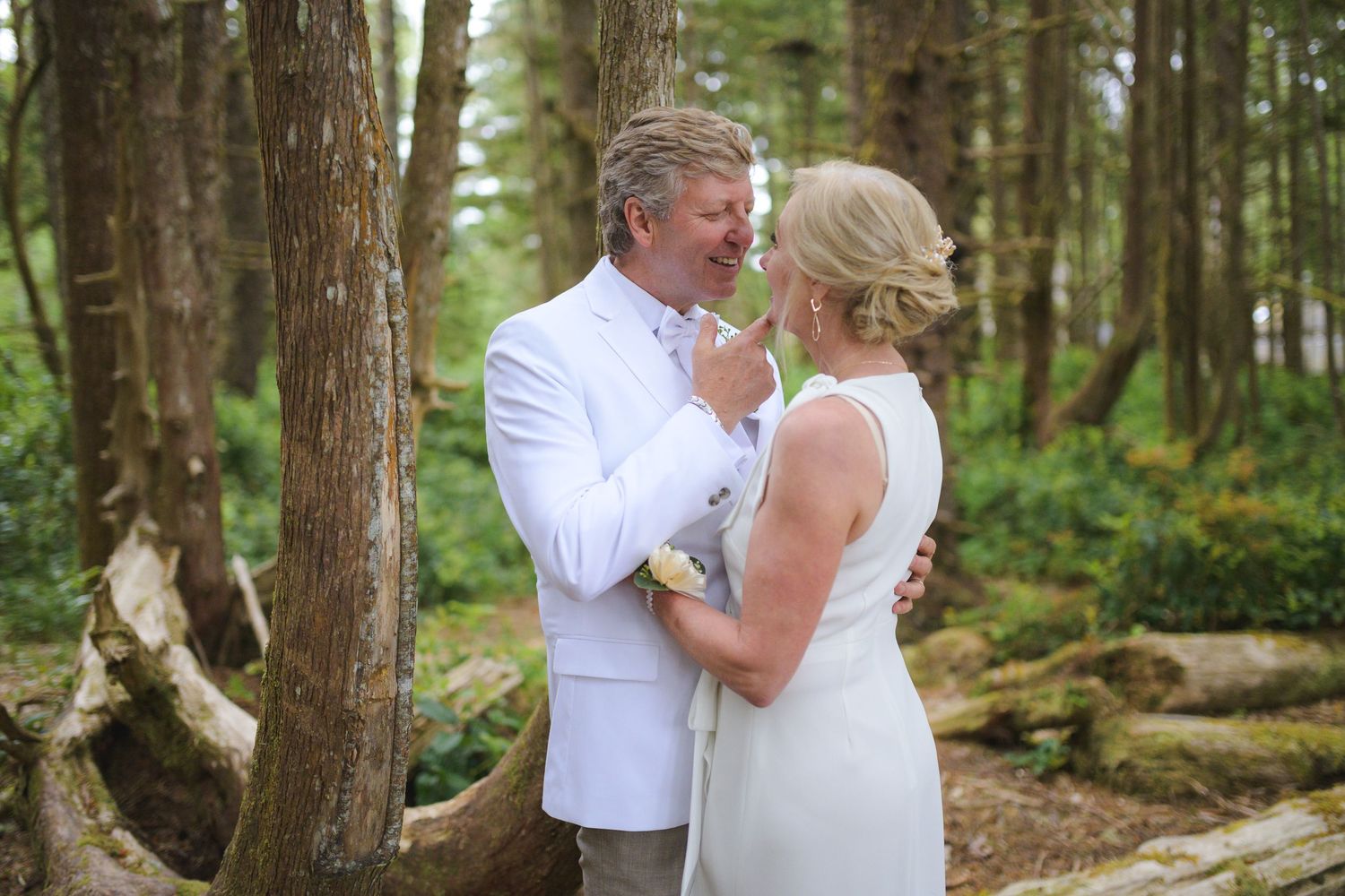 Romantic wedding couple embracing in a serene forest setting with tall trees.