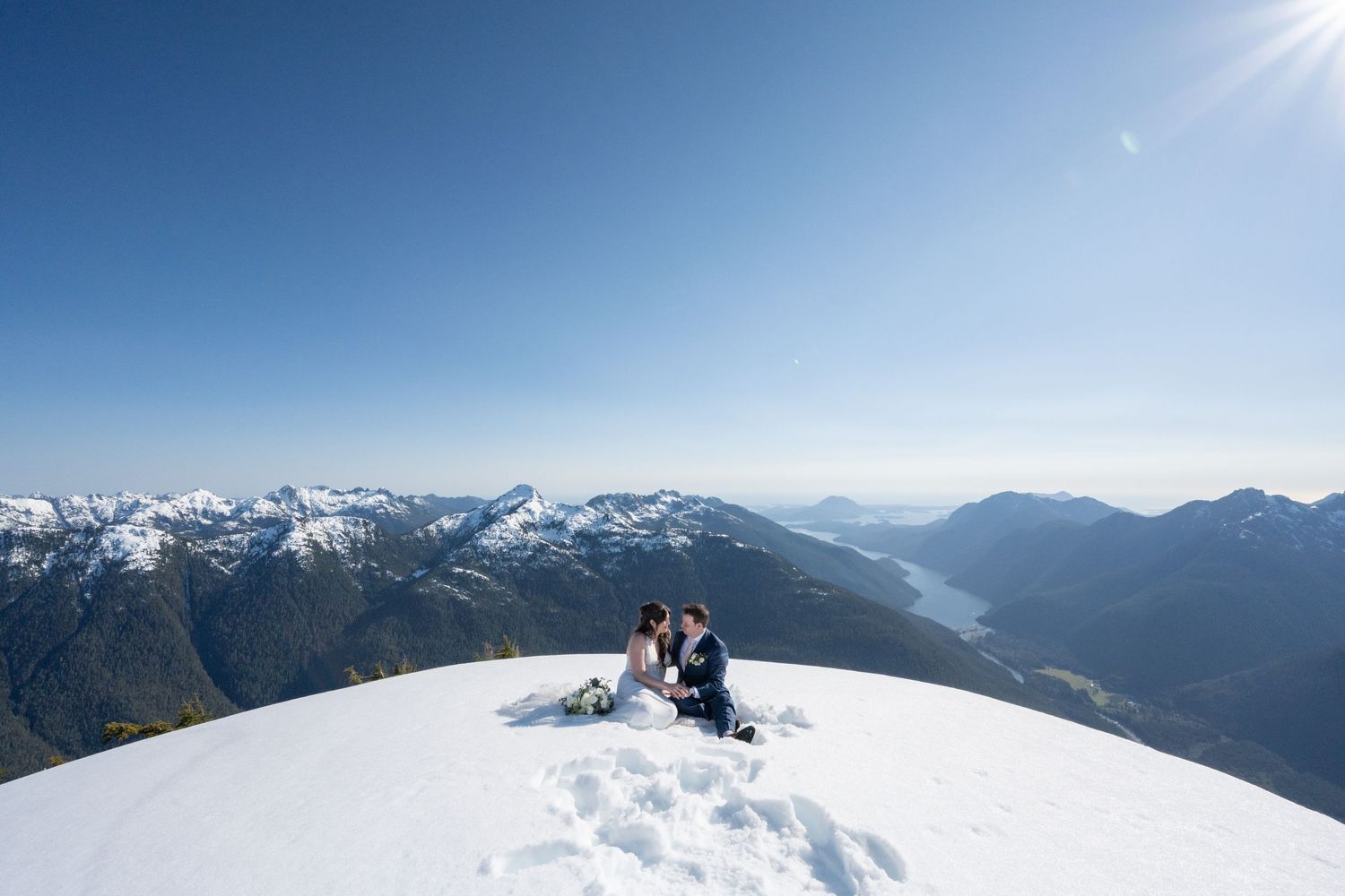 Panoramic view of snow-capped mountain ranges under bright blue sky.