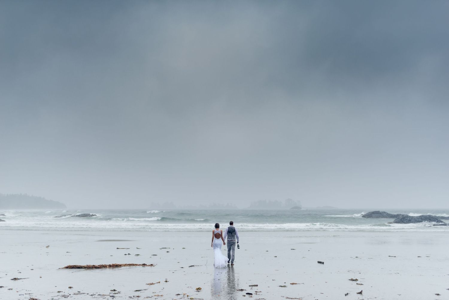 Foggy beach landscape with distant figures walking along the misty shoreline.