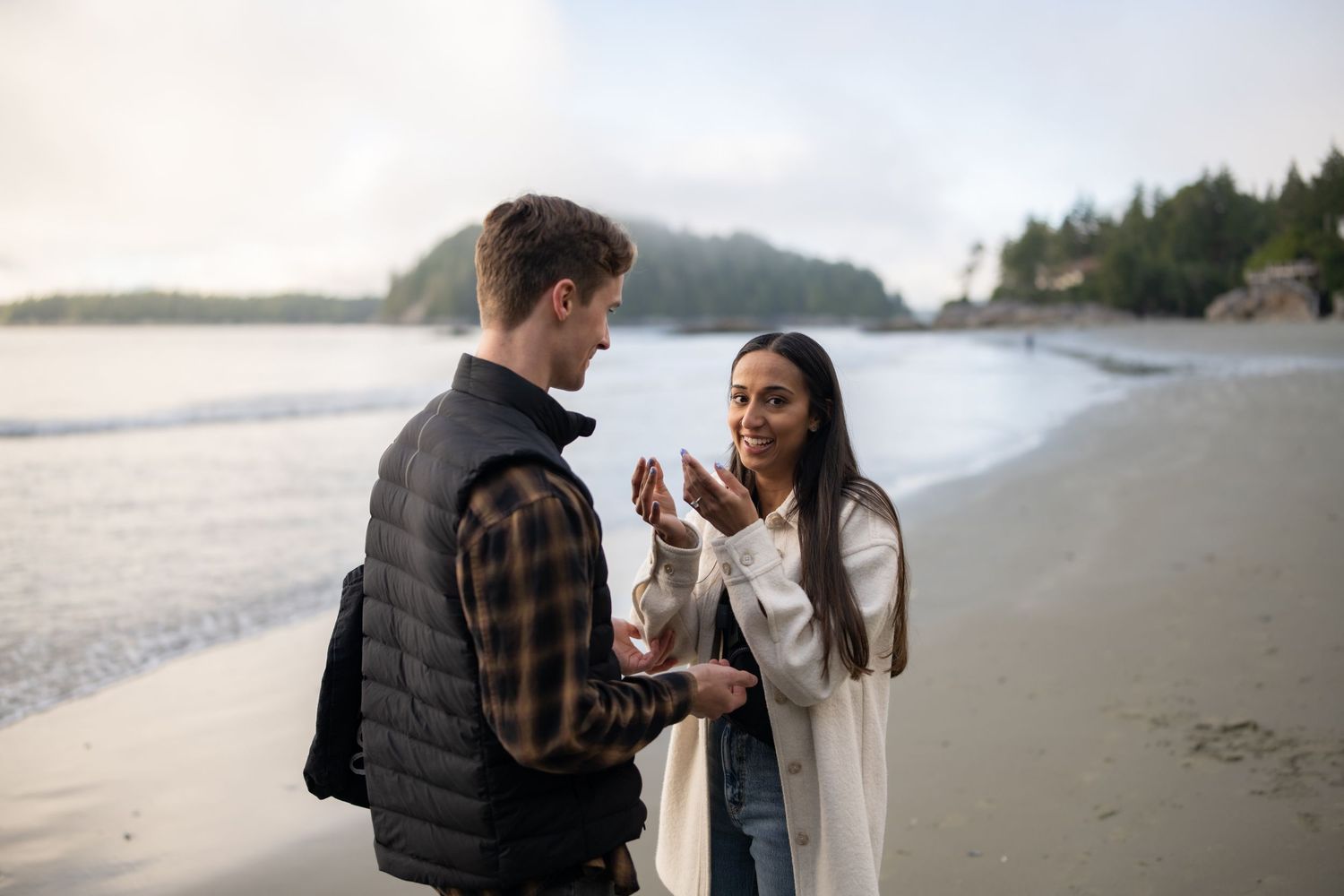 A couple shares an intimate moment on a scenic beach during their proposal.