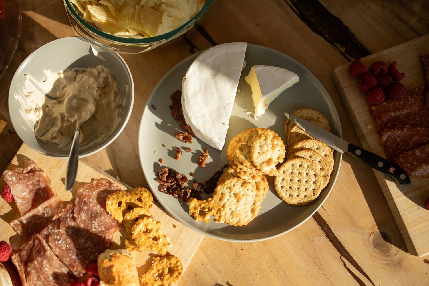 Appetizer spread featuring cheese, crackers and dips on rustic wooden surface.