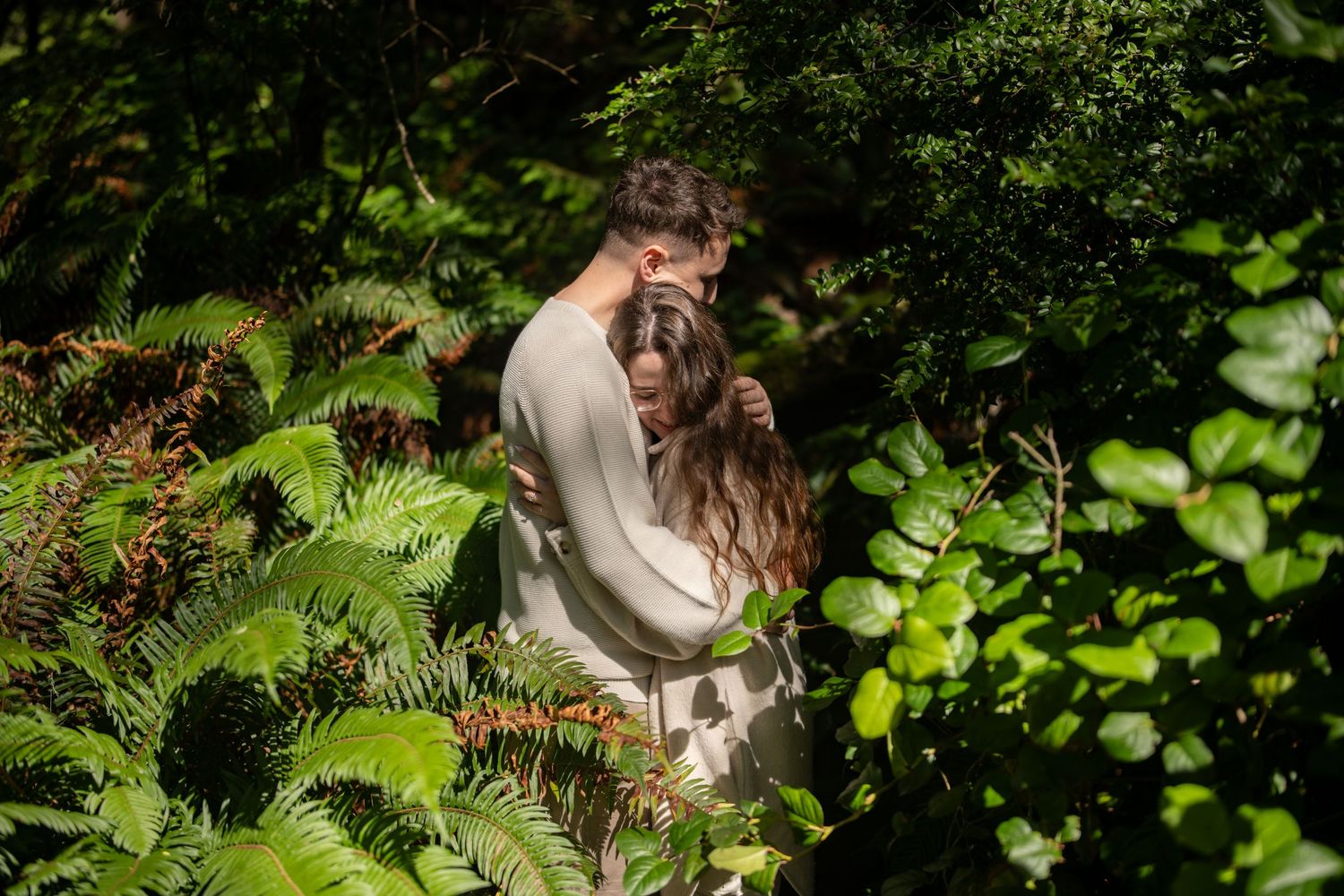 A romantic moment captured among lush green foliage in a forest setting.