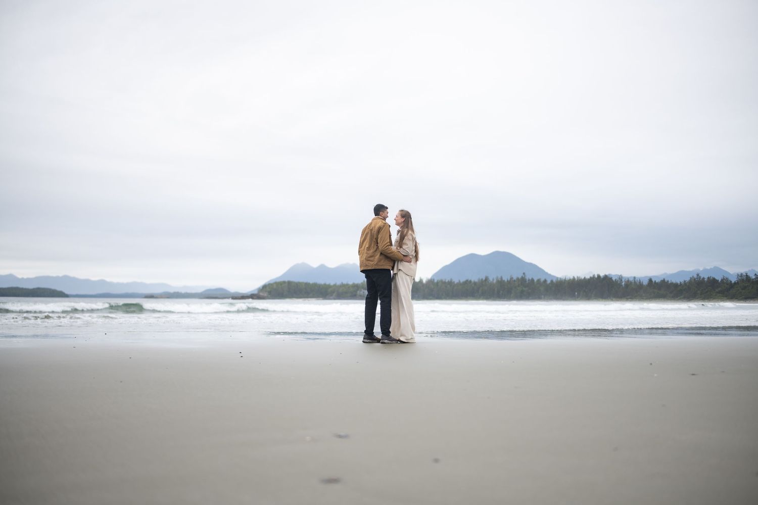 Misty coastal landscape with mountains and beach stretching into the distance.