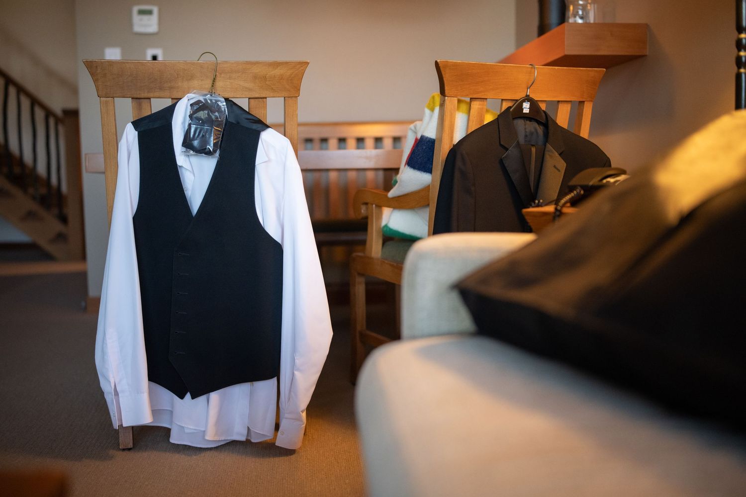 Formal black vests and white shirts hanging neatly on wooden hangers.