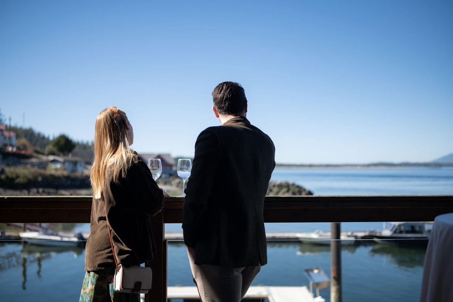 Scenic waterfront gathering with mountains and blue sky in background.