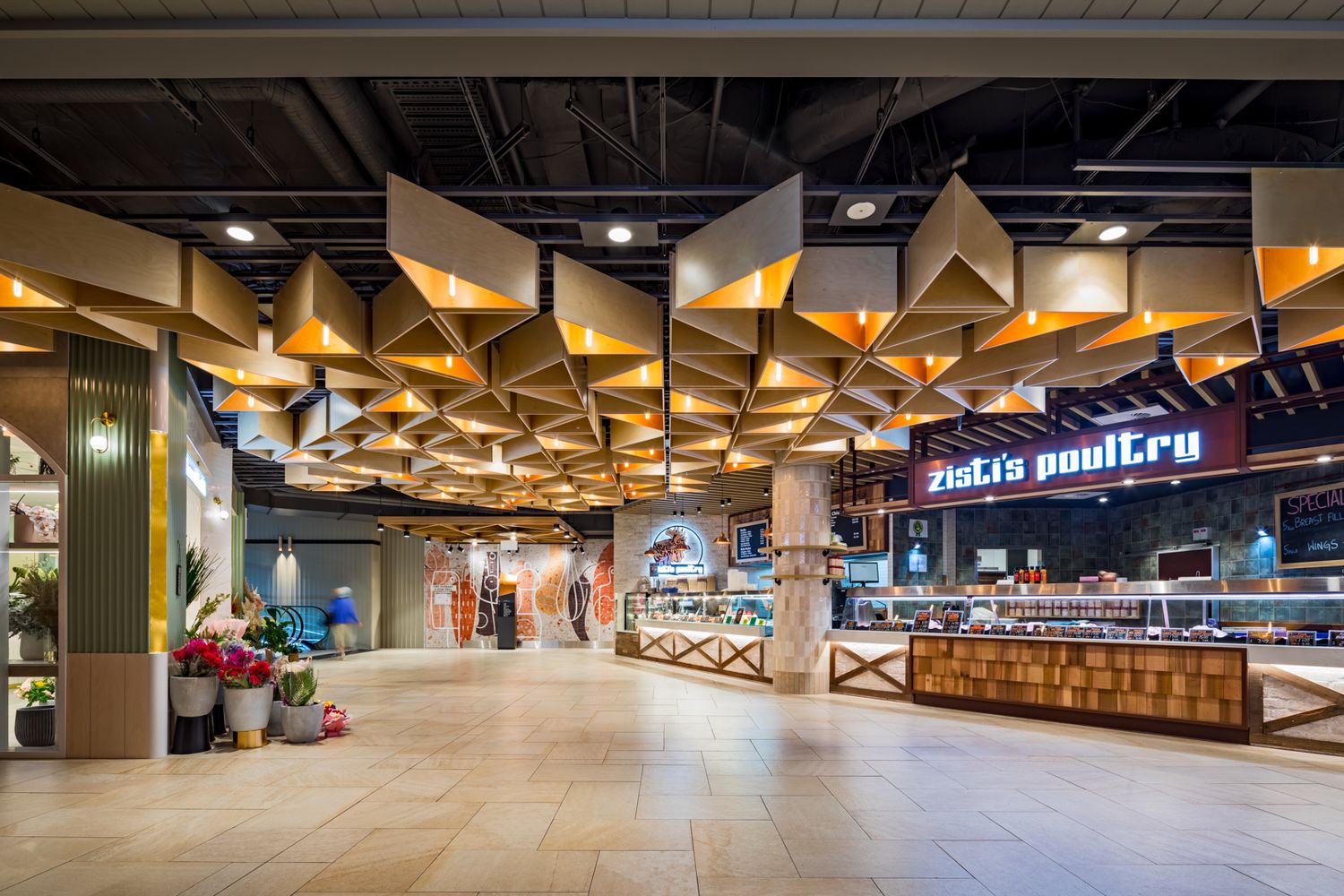 Spacious shopping centre food hall with a geometric golden ceiling, a Fish and Poultry market counter and polished stone flooring.