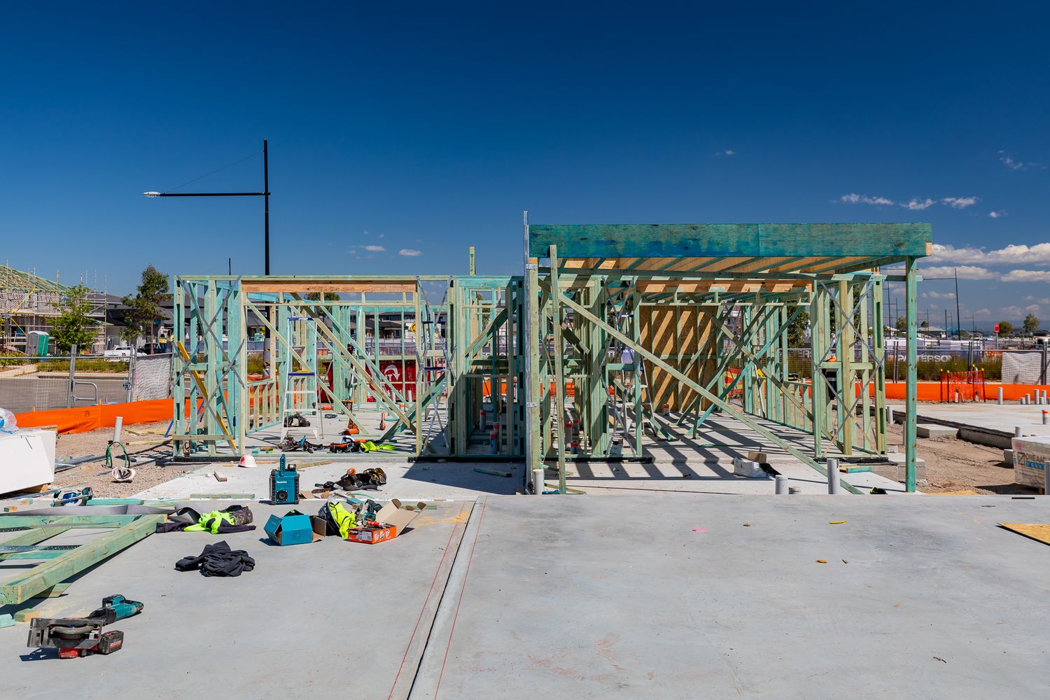 Timber framing of new homes on concrete slabs with workers' tools and boots scattered across a residential building site.