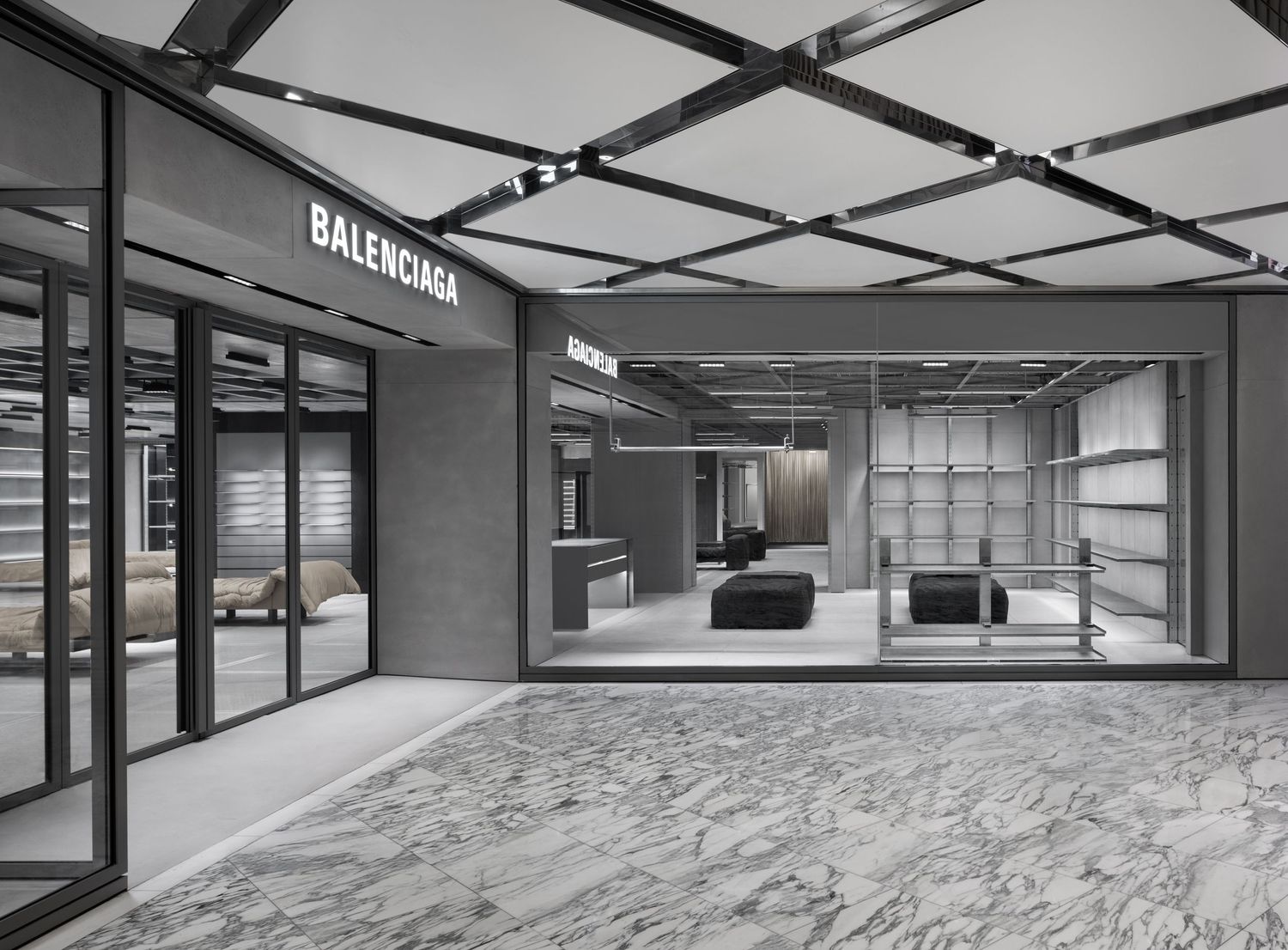 Balenciaga store interior with a grid ceiling, marble floors, glass-fronted displays, and sleek shelving in a modern retail space.
