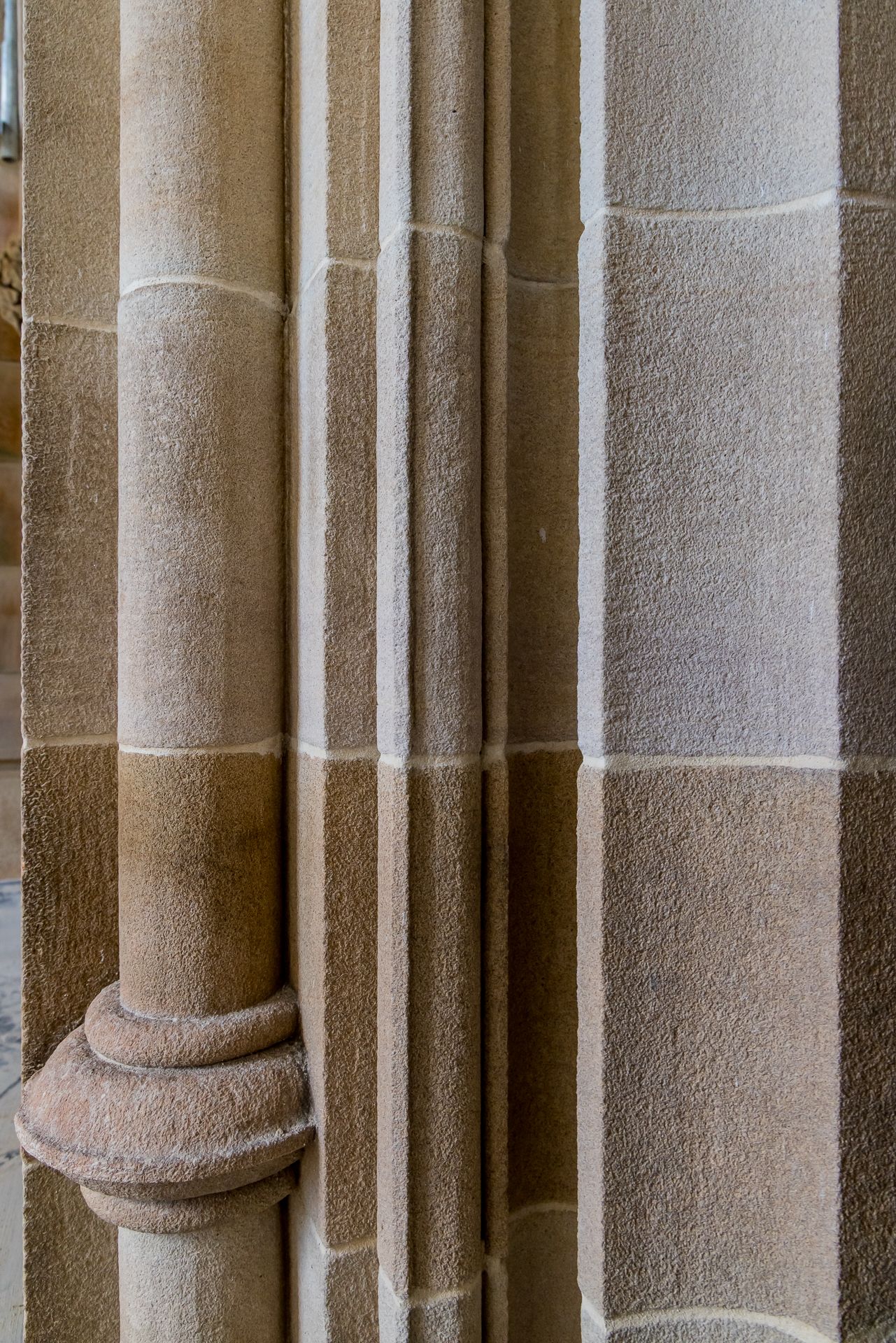 Vertical view of clustered sandstone columns with a stacked, ringed base showing fine stone texture and joints.