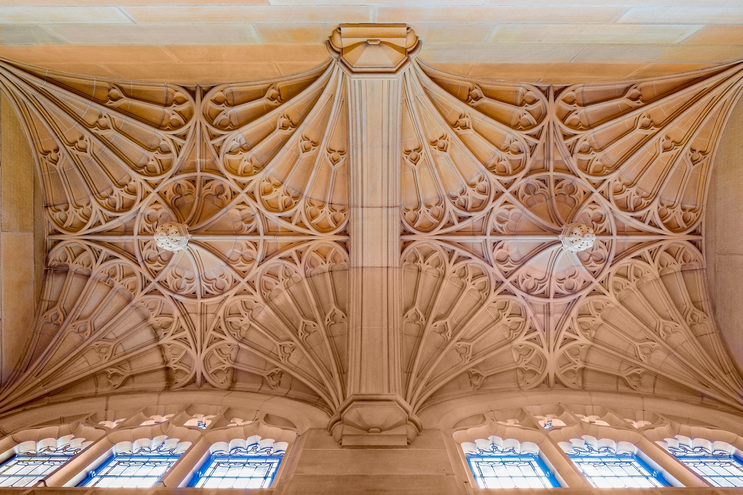 Ornate Gothic fan-vaulted sandstone ceiling with carved ribs and decorative stained glass windows along the lower edge.