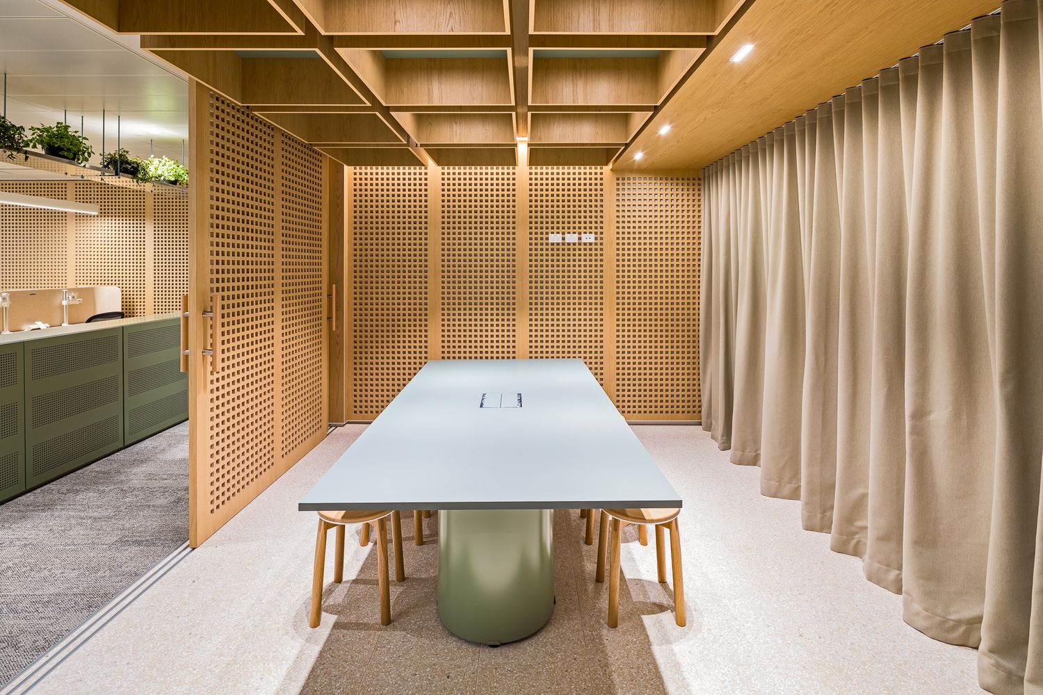 Elegant meeting room with a pale blue table, timber slatted walls, wooden stools and a floor-to-ceiling taupe curtain.