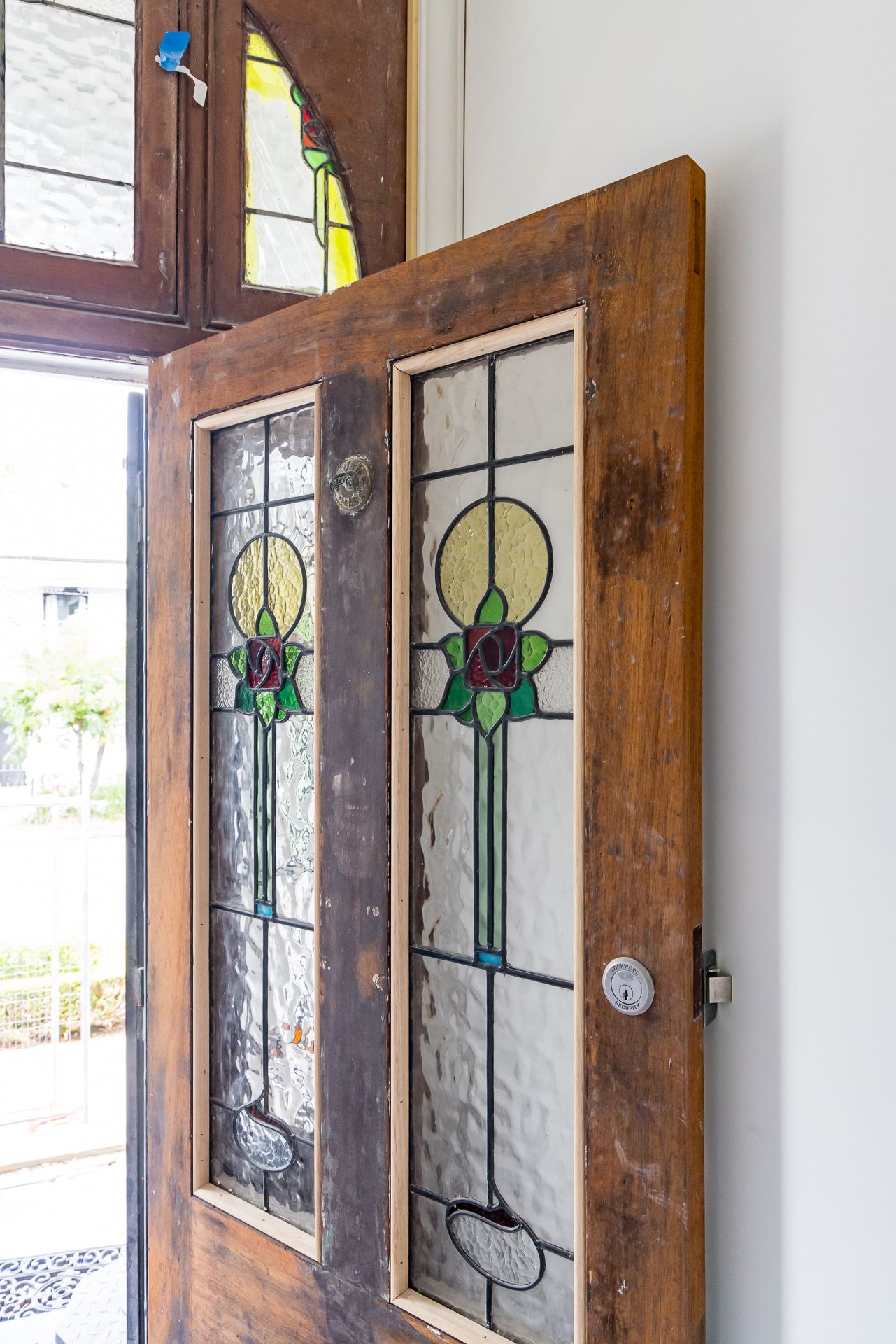 Open timber front door with leadlight glass panels featuring a red rose and green leaf Art Nouveau design.