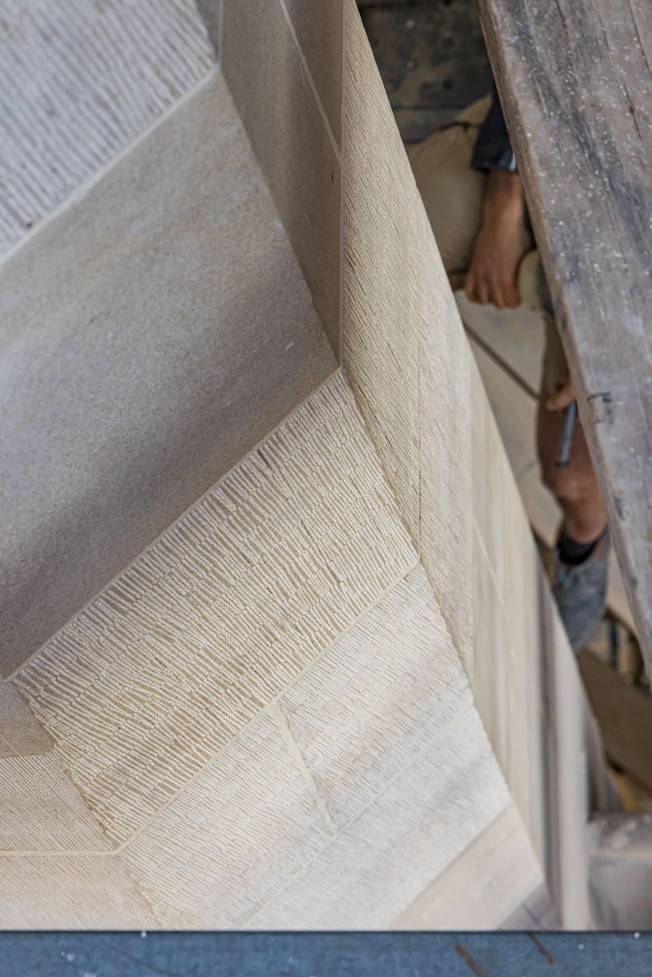 Close-up of freshly carved sandstone block showing fine chiseled texture and angled edges on a construction site.