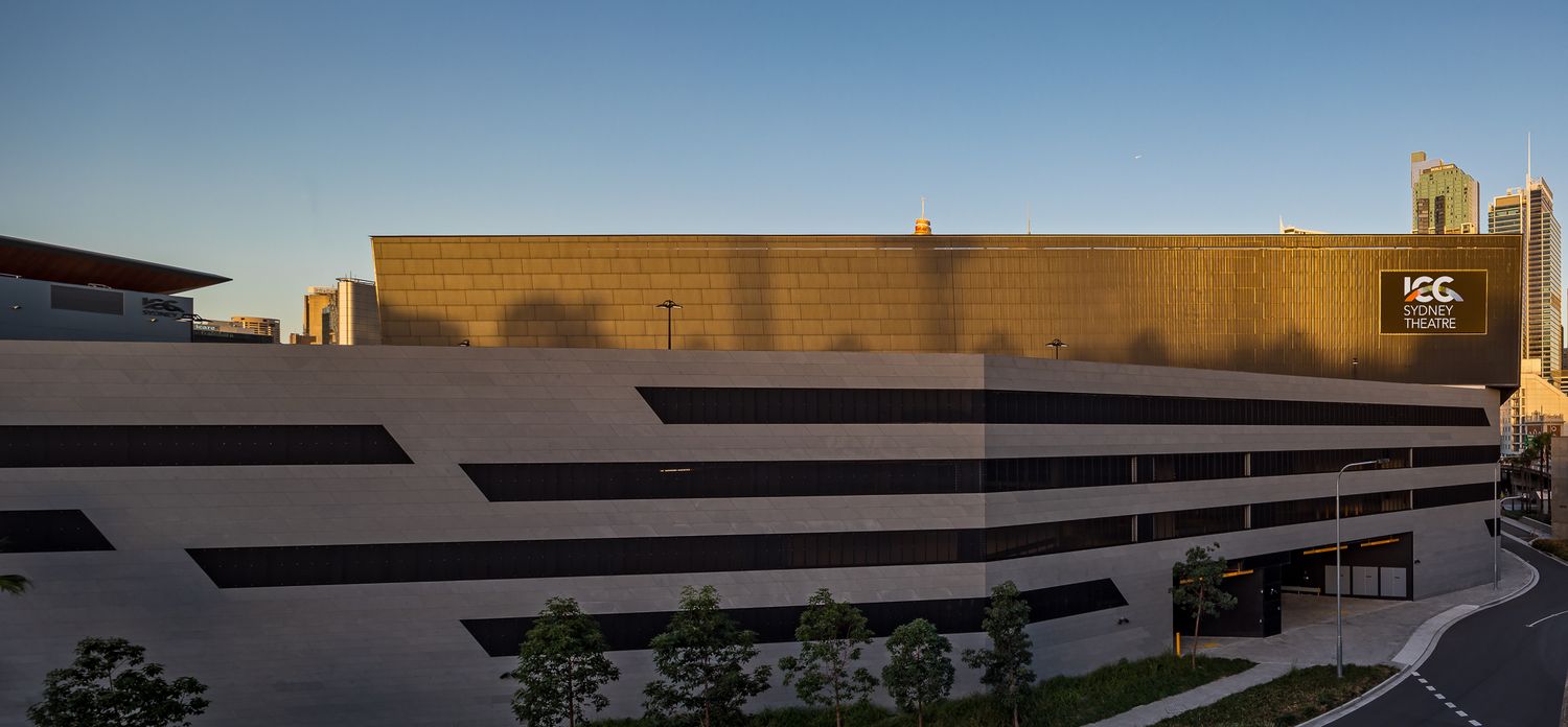 Large modern exhibition building with a bronze facade and horizontal dark window bands at golden hour.