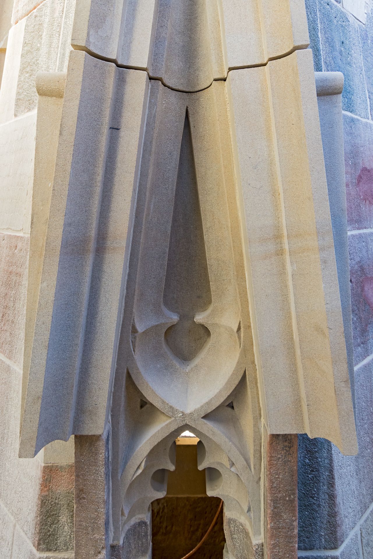 Carved stone column detail with Gothic tracery, pointed arch shapes and pleated stone folds meeting at a narrow opening.