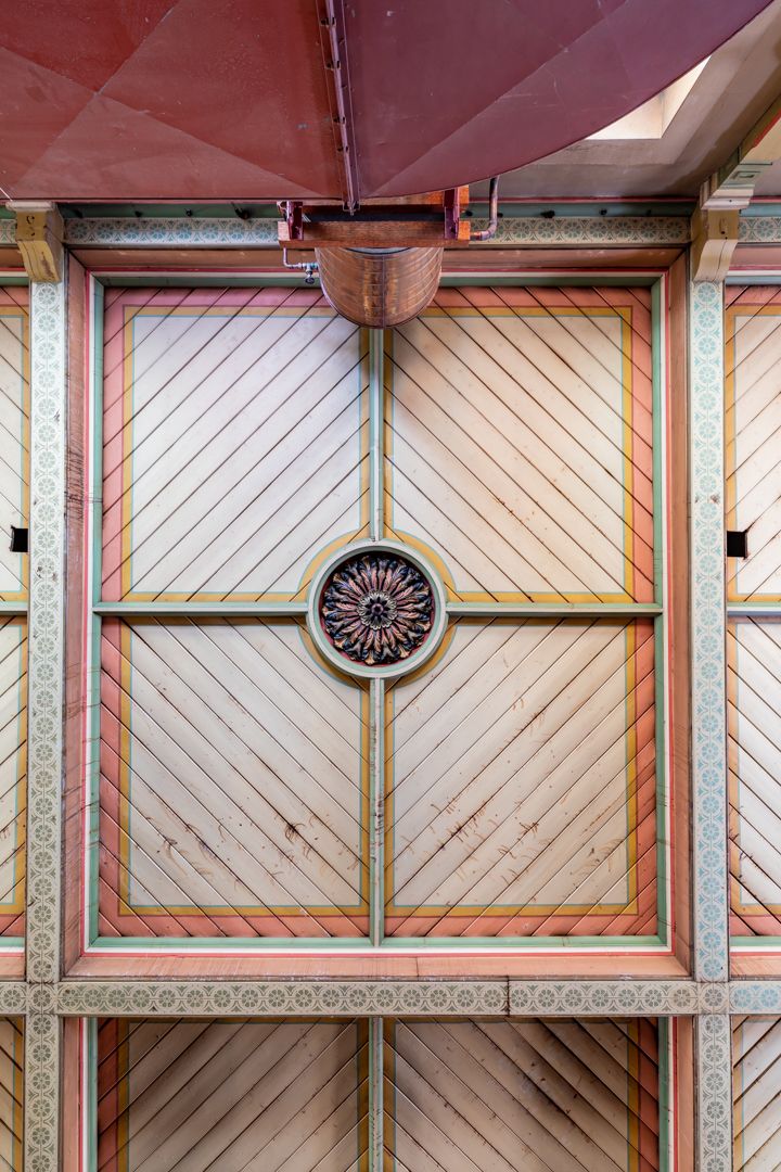 Ornate painted timber ceiling with diagonal panels, decorative borders and a central carved rosette medallion.
